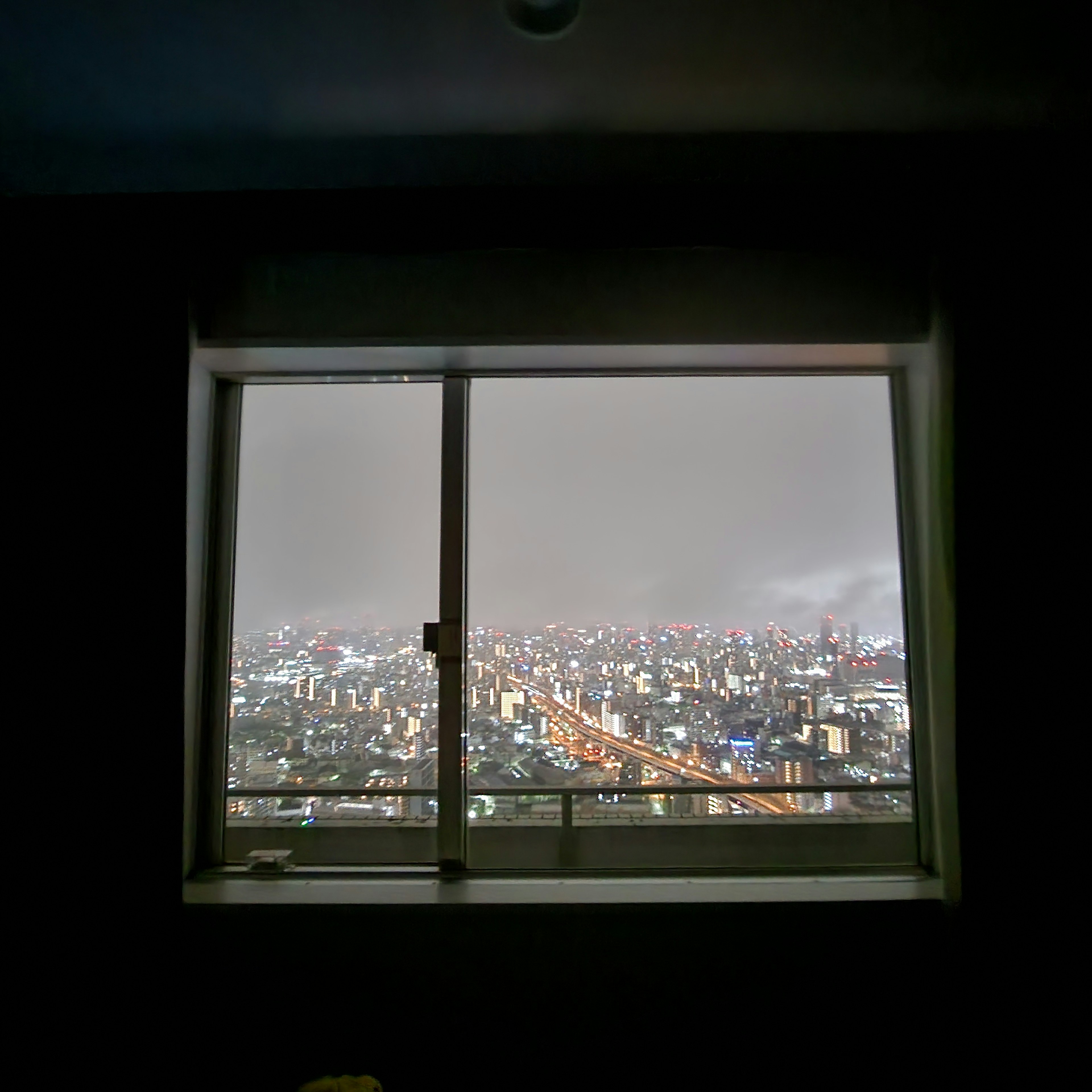 高層ビルの窓から見える都市の風景 明るい夜景と霧がかかった空