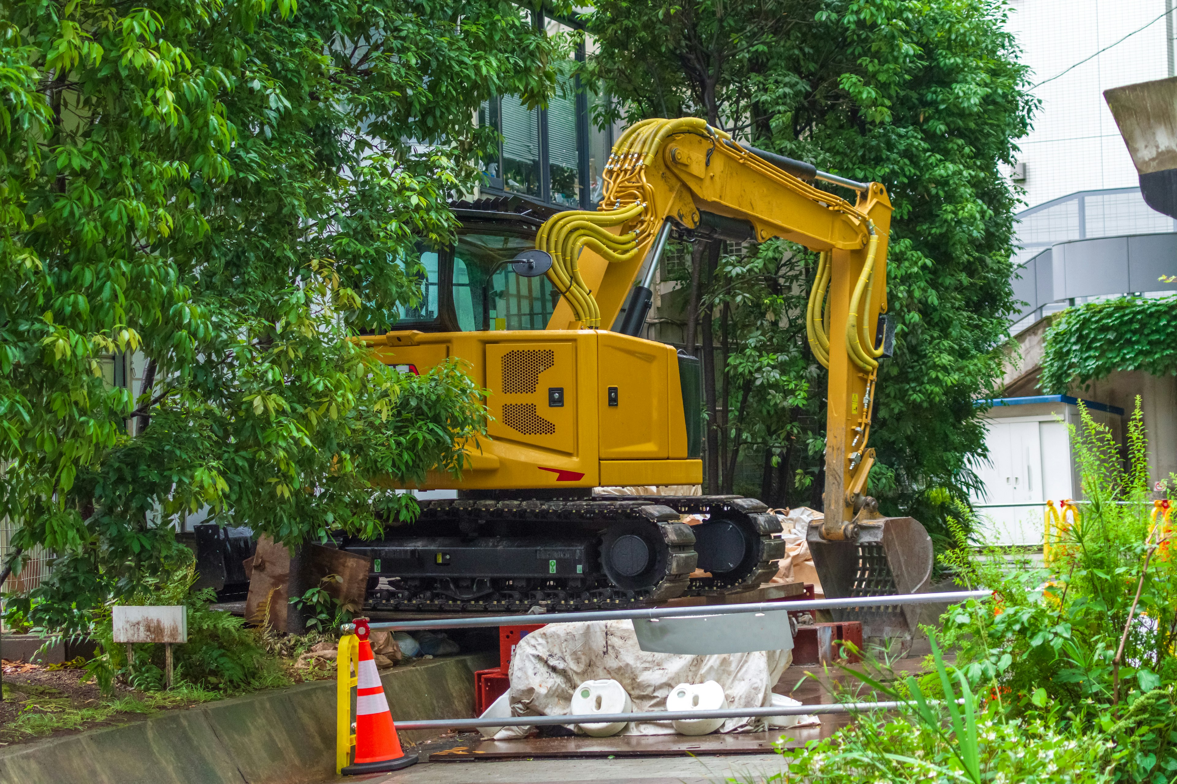 Yellow excavator working at a construction site surrounded by greenery