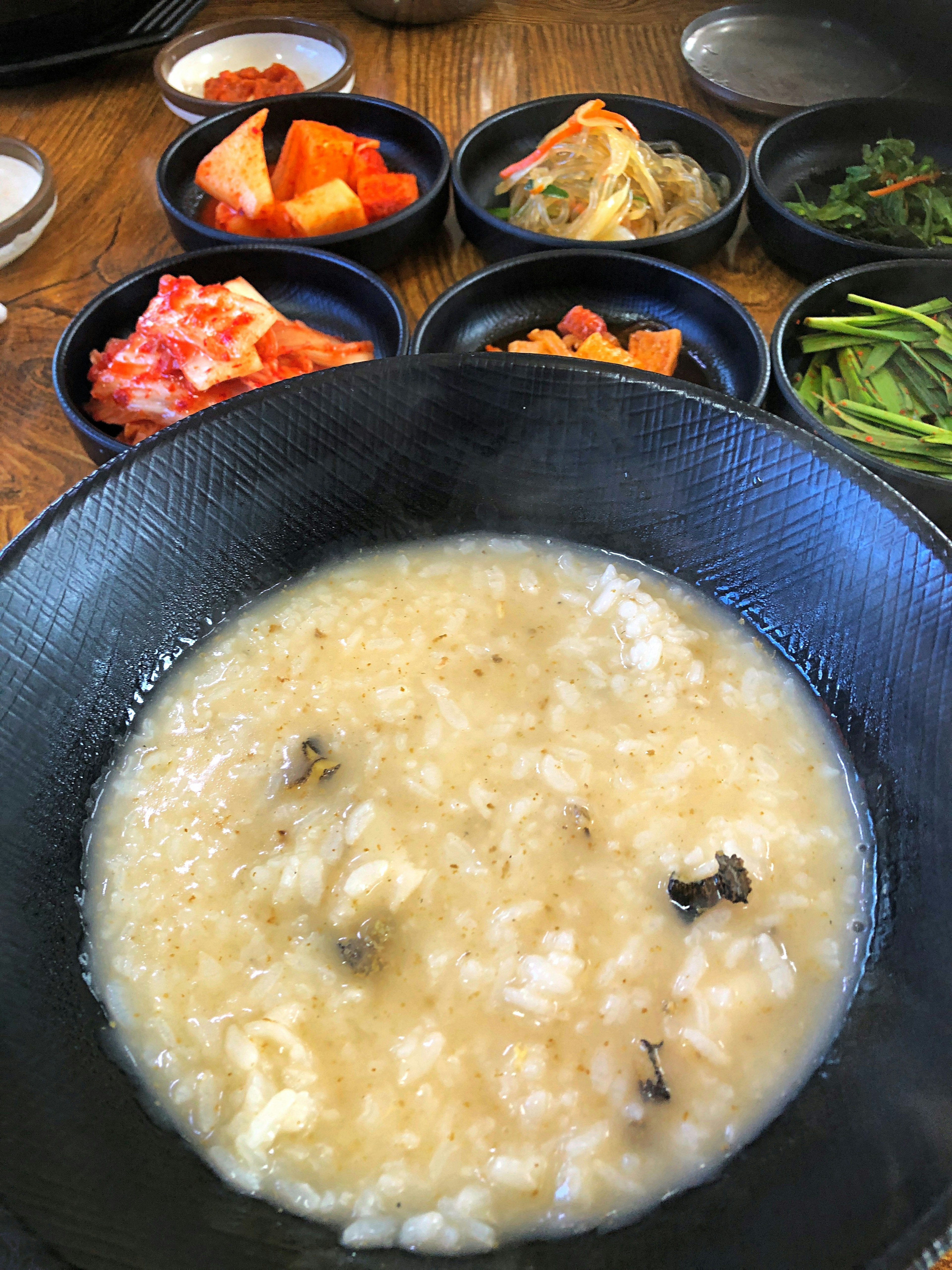 Porridge de arroz en un tazón negro con guarniciones de kimchi