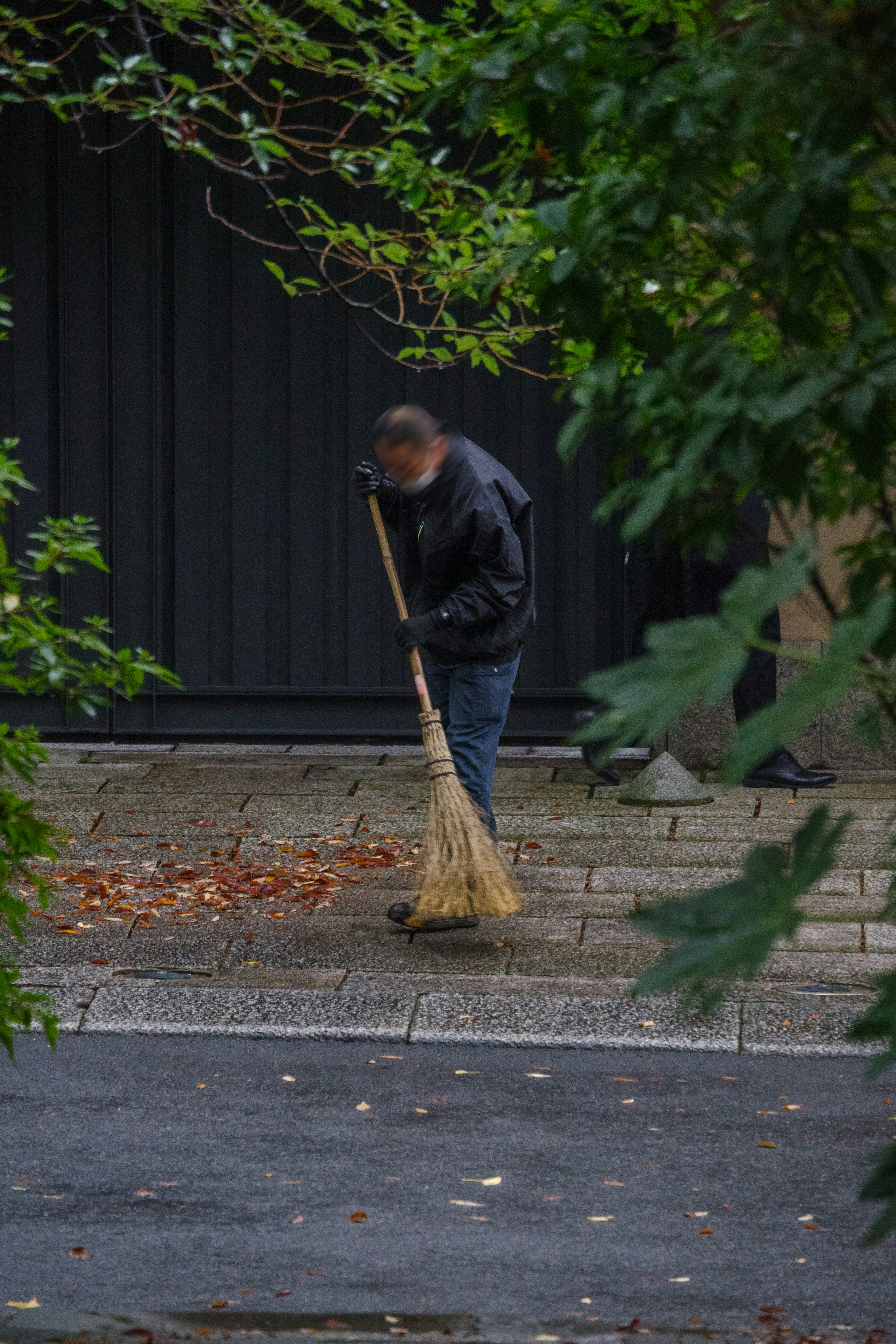 男性が掃き broom で道を掃除している様子