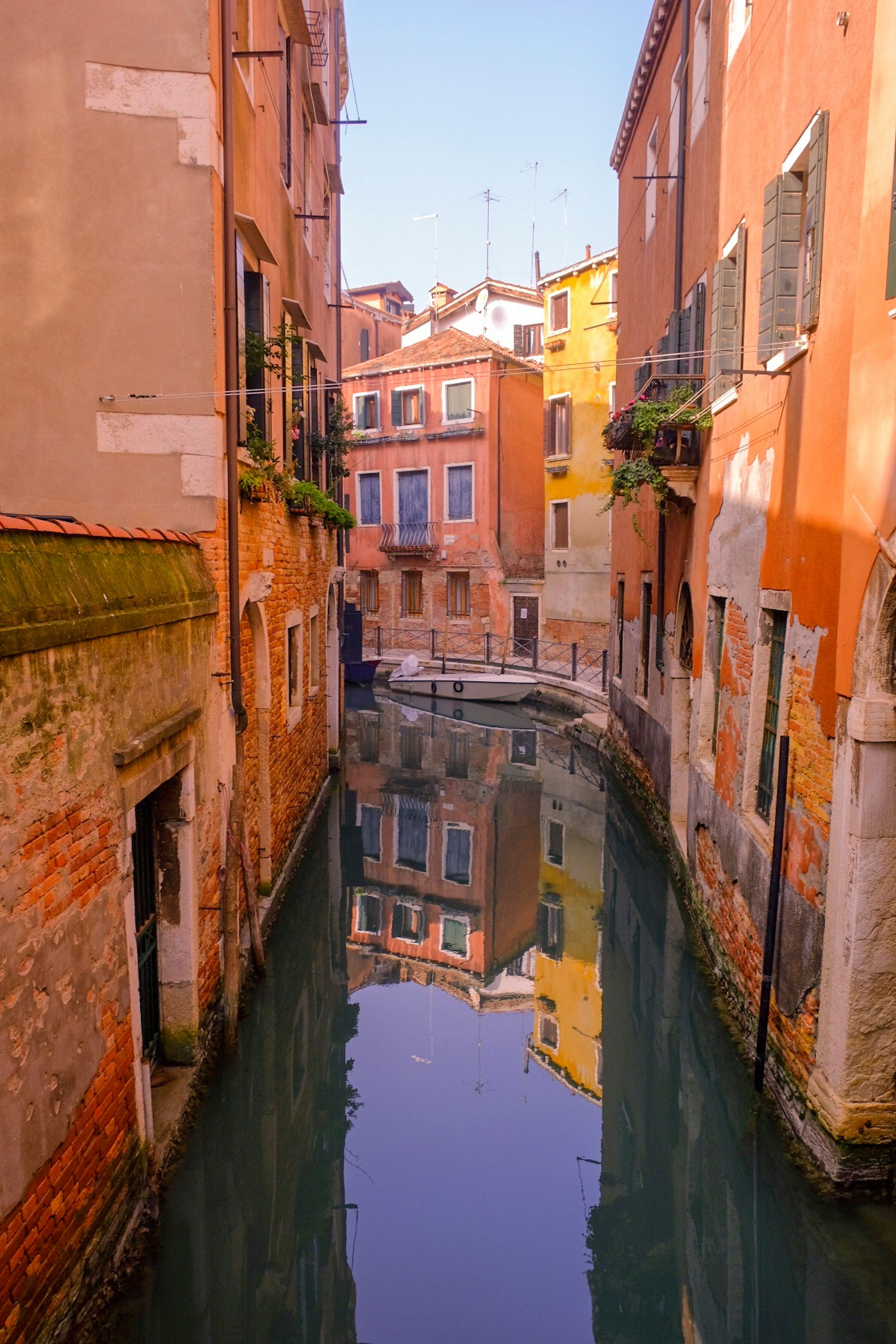 Canal estrecho en Venecia reflejando edificios coloridos