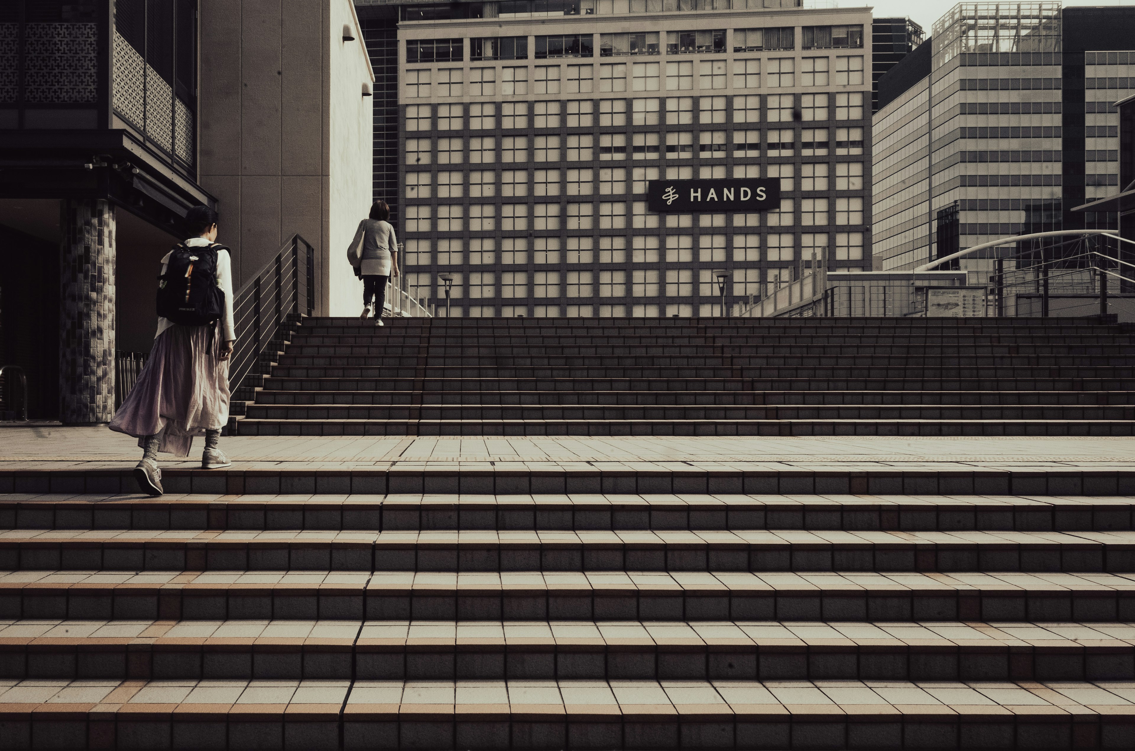 Personas subiendo escaleras con edificios al fondo