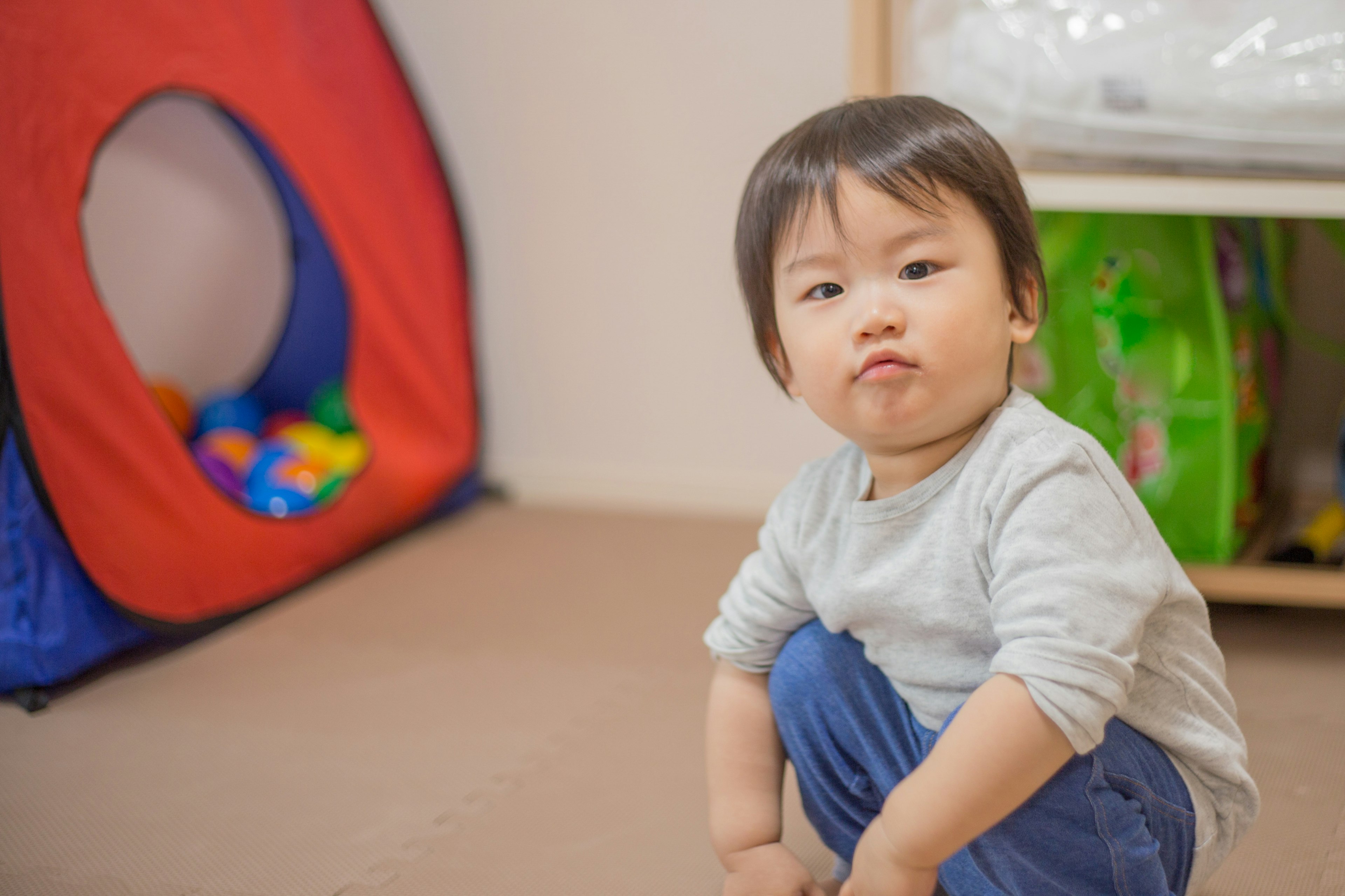 赤い遊び場の近くで座っている幼児