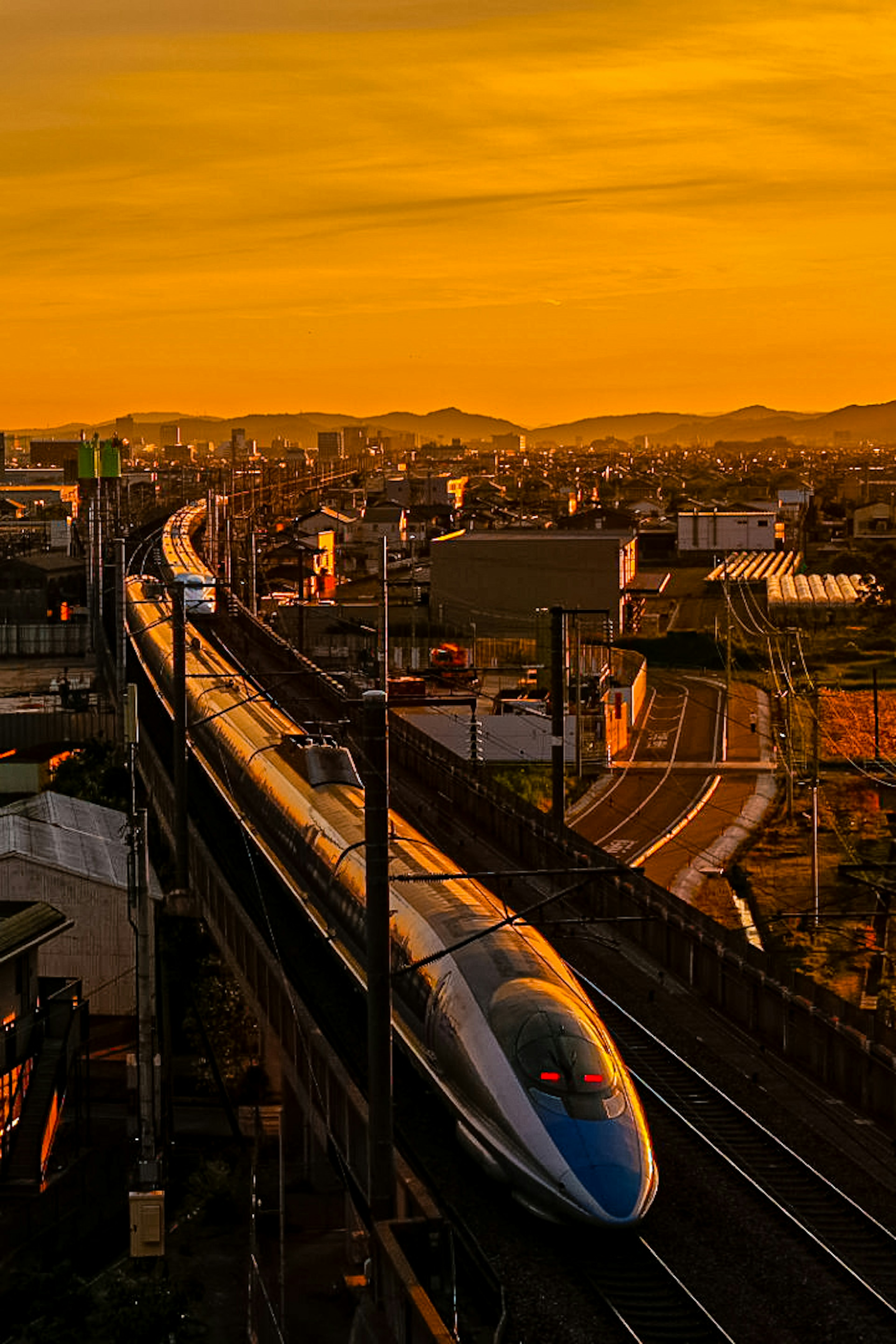 夕焼けの中を走る新幹線と都市の風景