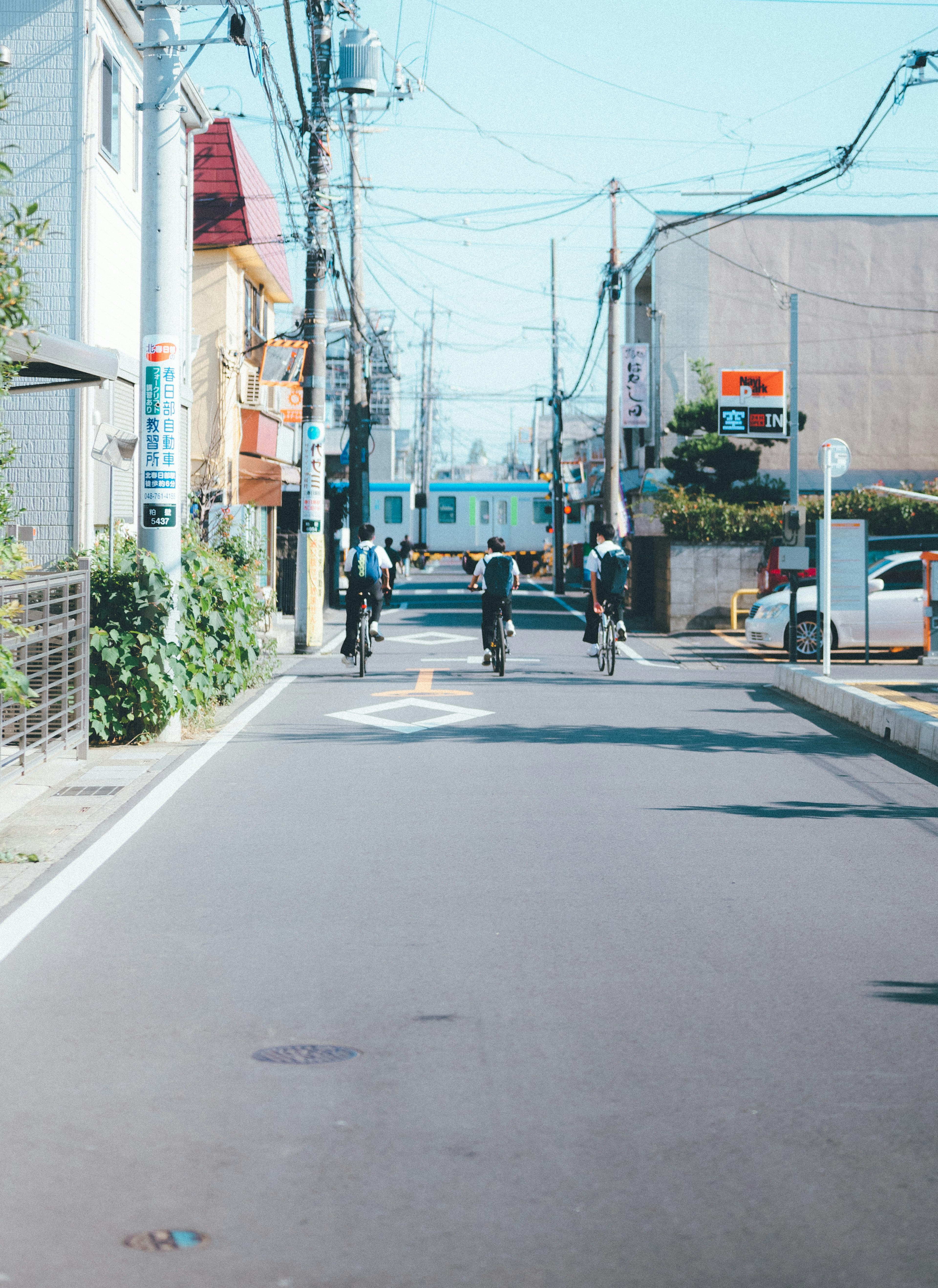 Une scène de rue tranquille avec des personnes à vélo sous un ciel bleu