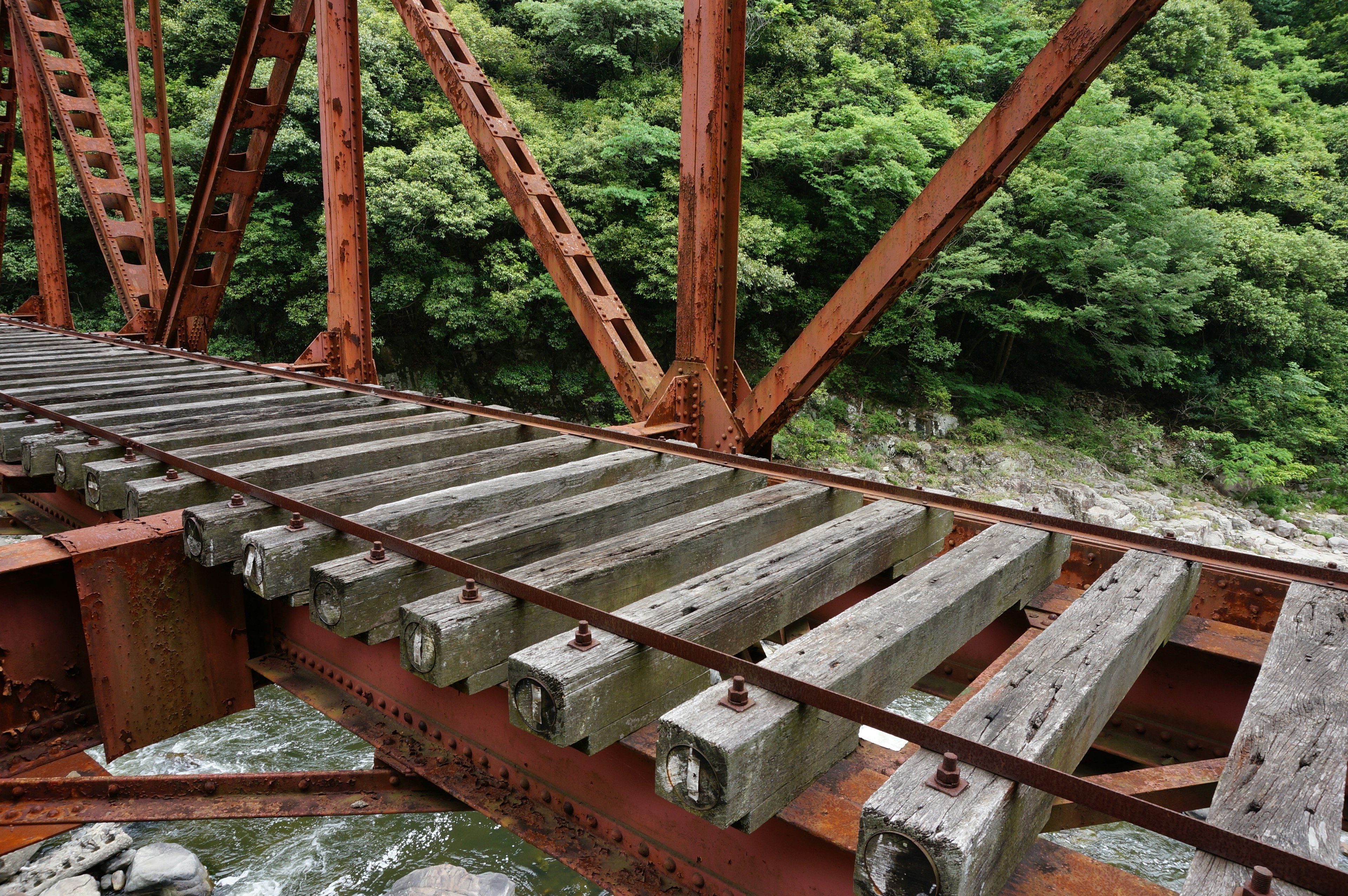 Rostige Eisenbrücke mit Holzplanken und üppigem grünem Hintergrund