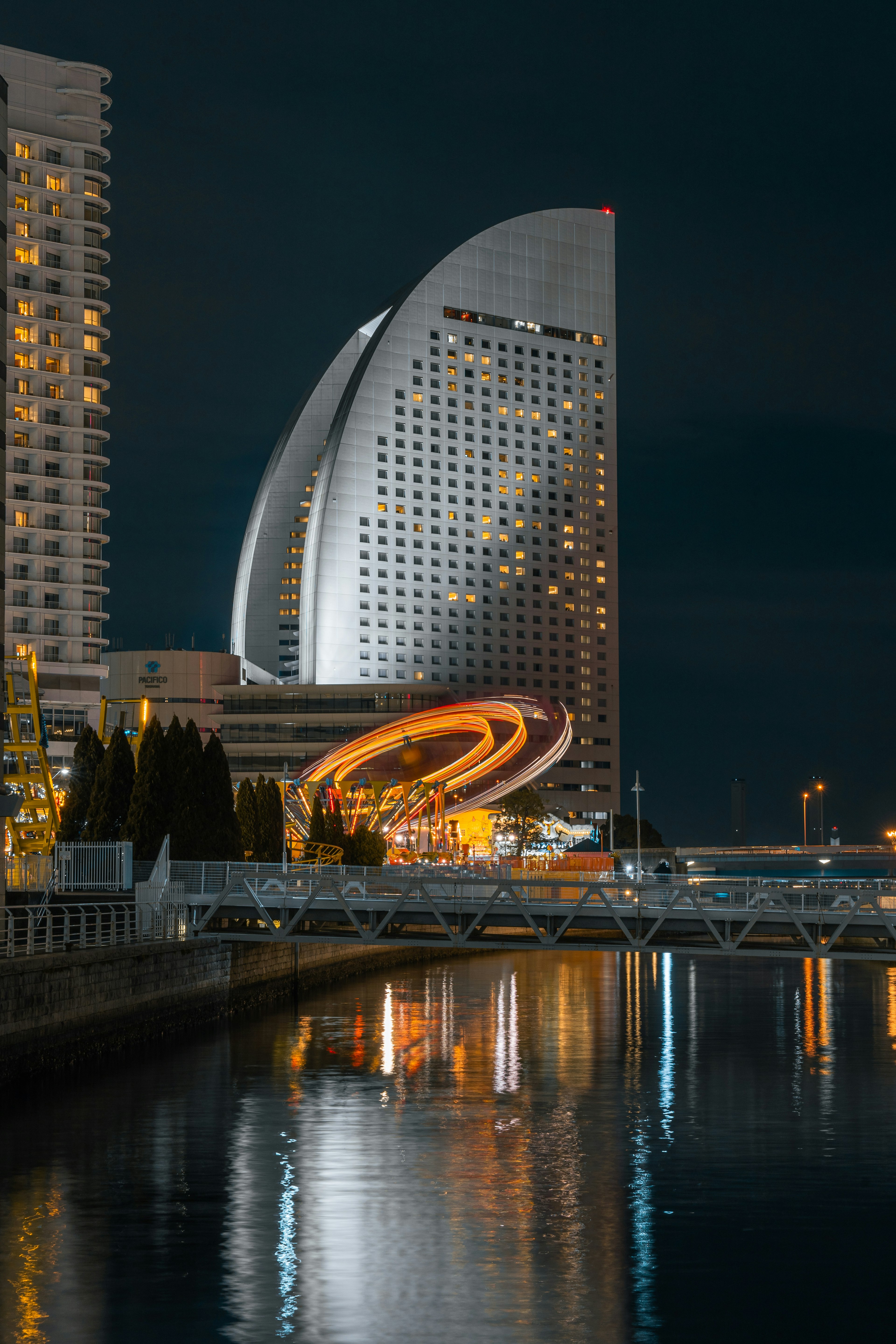 Edificio futurista en Yokohama de noche con reflejos en el agua