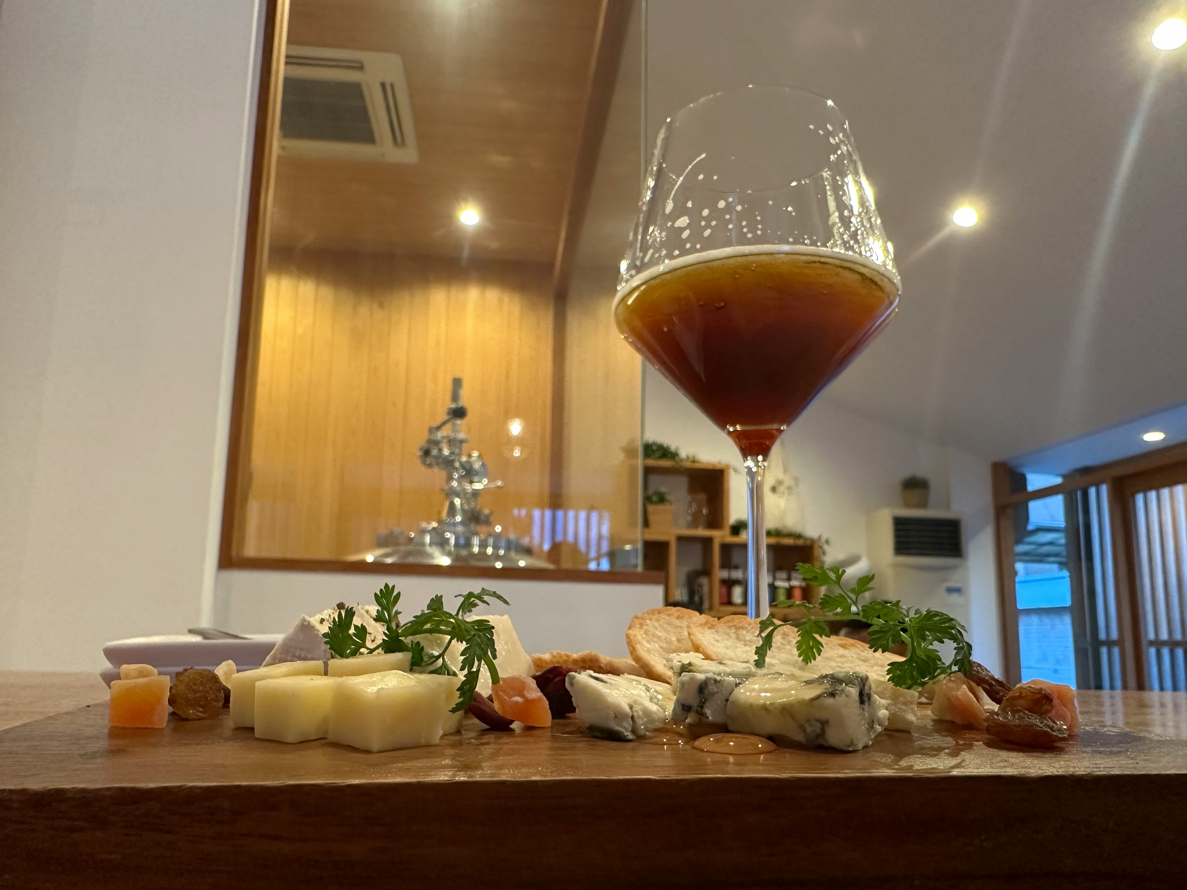 A glass of dark beer beside a seafood platter on a wooden table