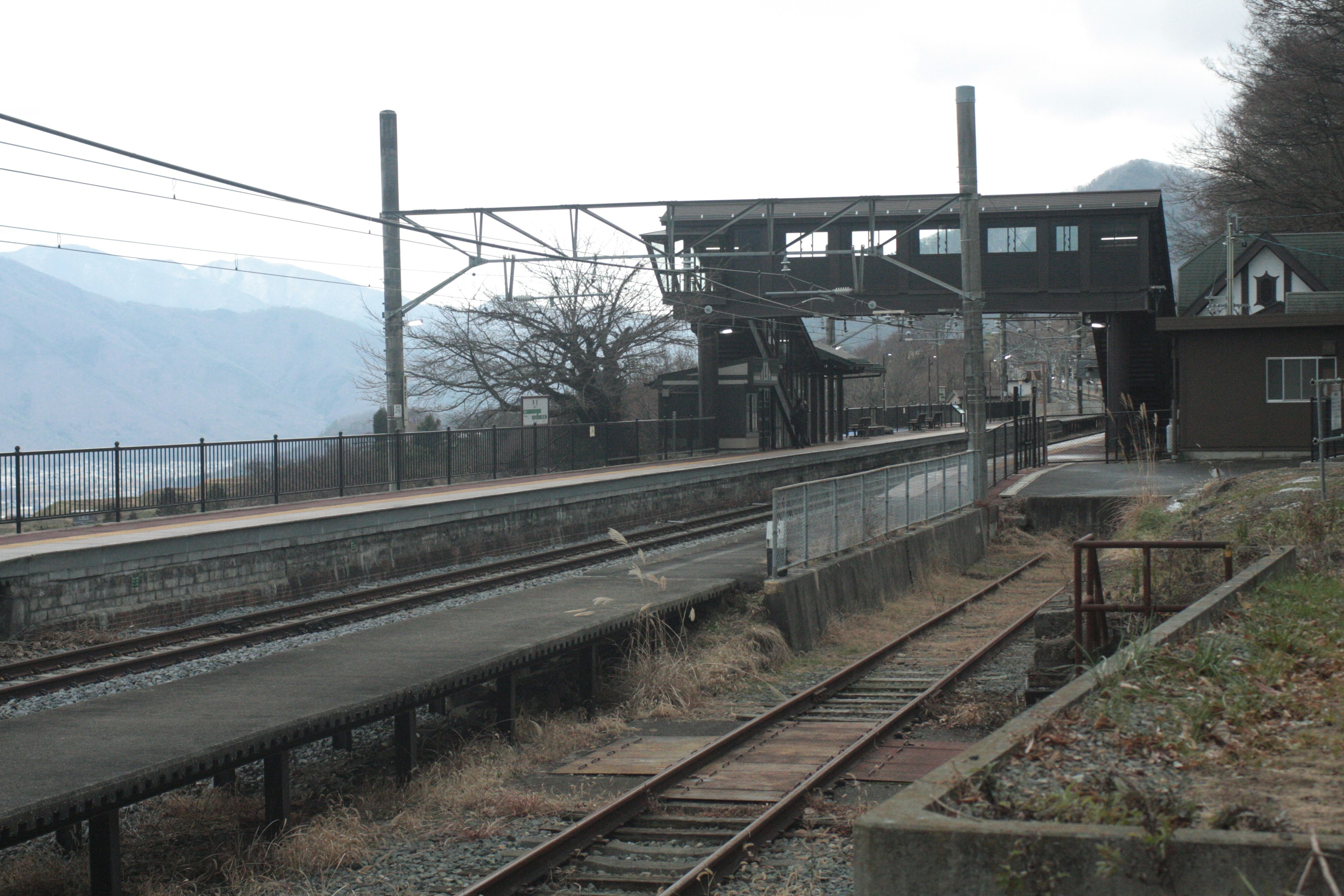 Quiet train station scene with railway tracks and platform surrounded by mountains