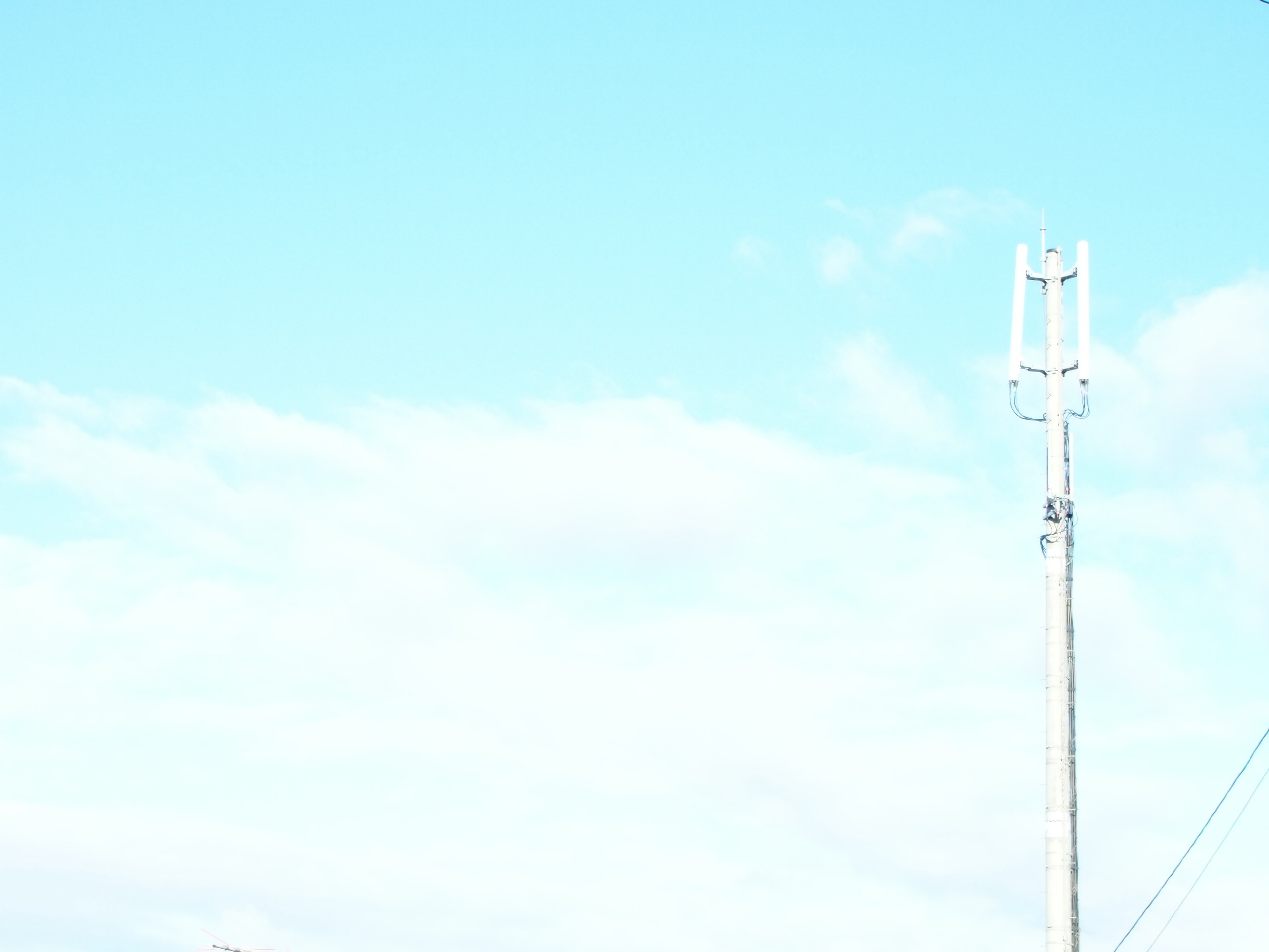 Eine Landschaft mit einem Strommast vor einem blauen Himmel mit Wolken