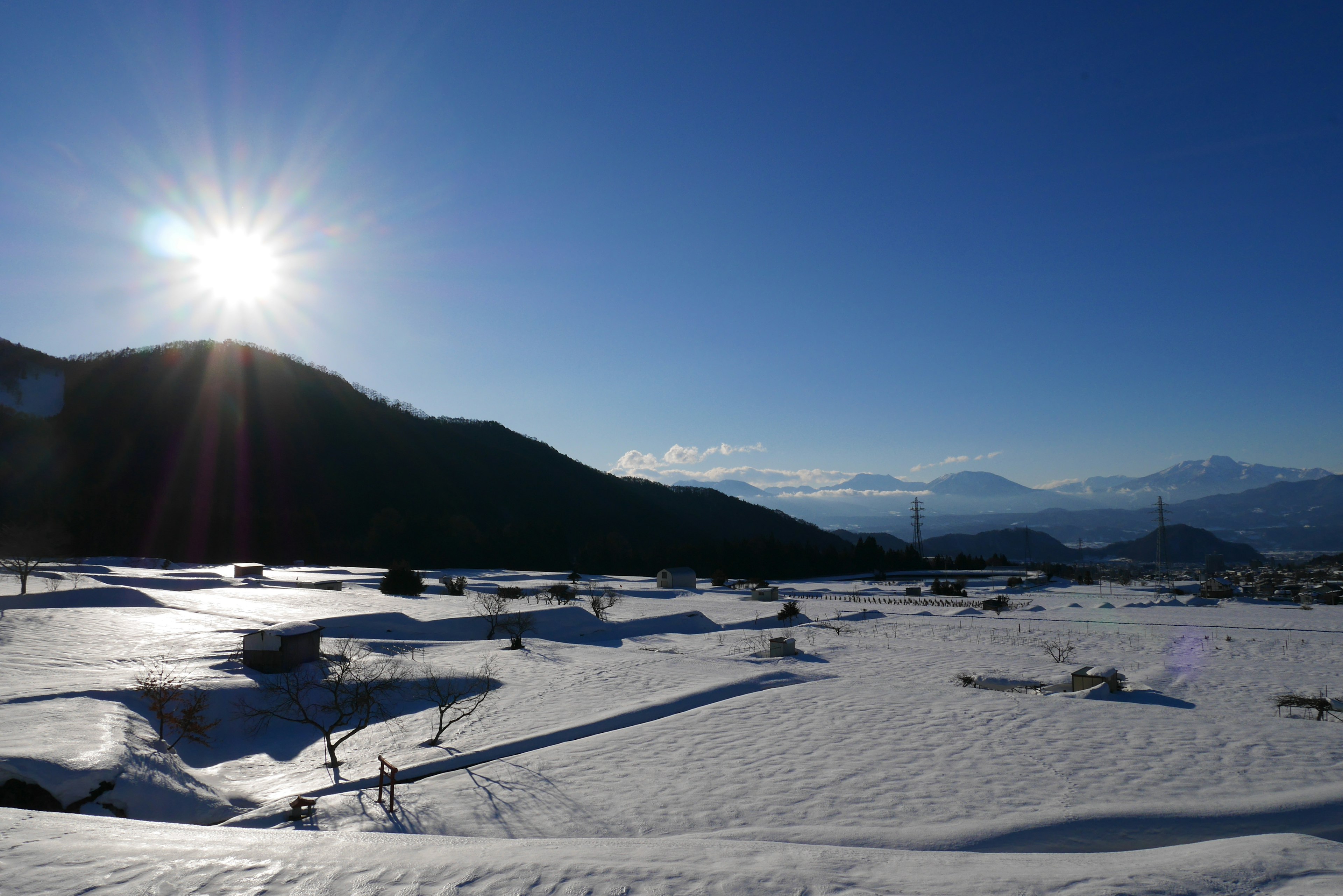 Snow-covered landscape with sun shining in clear blue sky