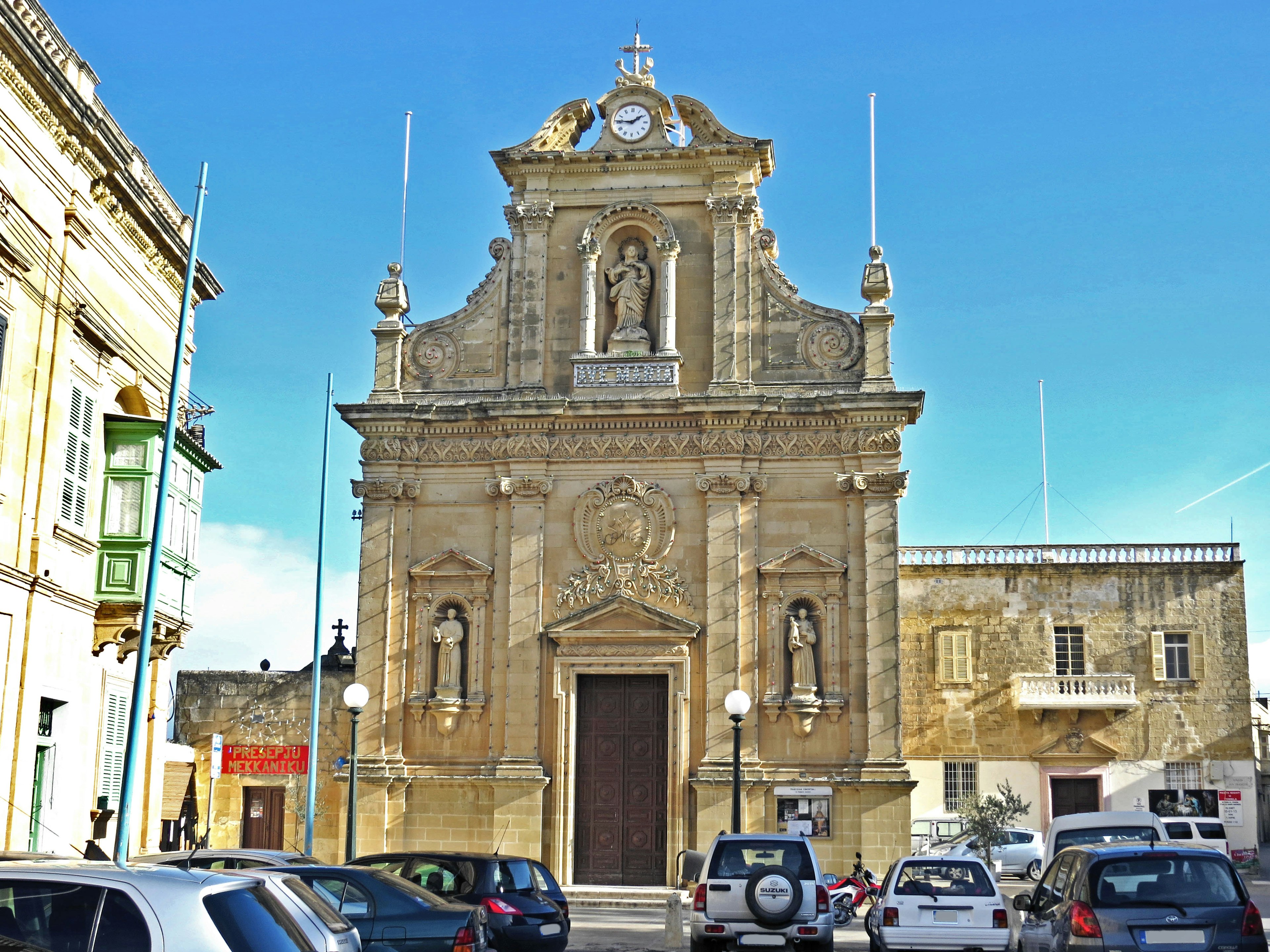 Façade d'une belle église avec un ciel bleu et des voitures garées