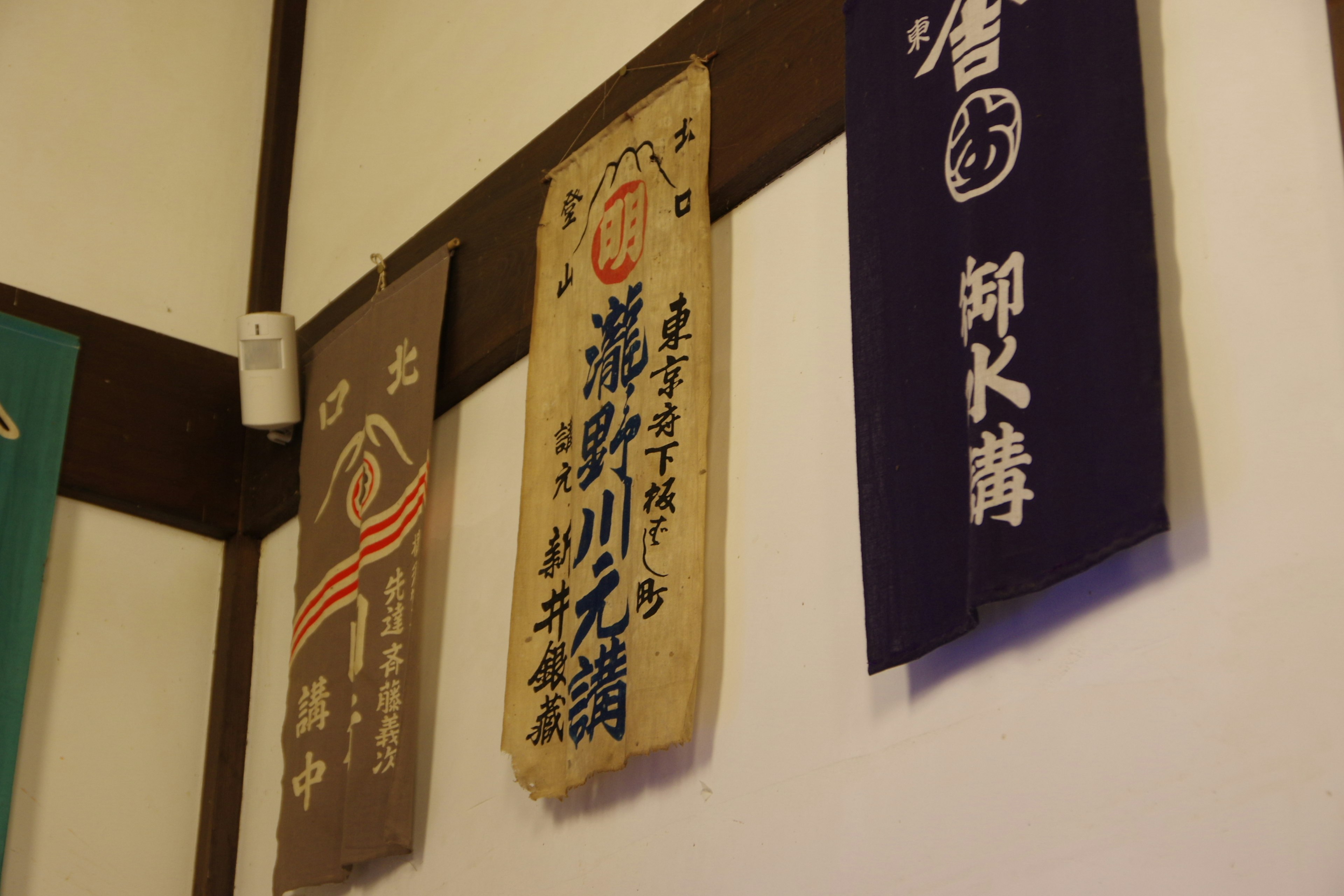 Traditionelles japanisches Noren, das an der Wand hängt, mit Farben und Text