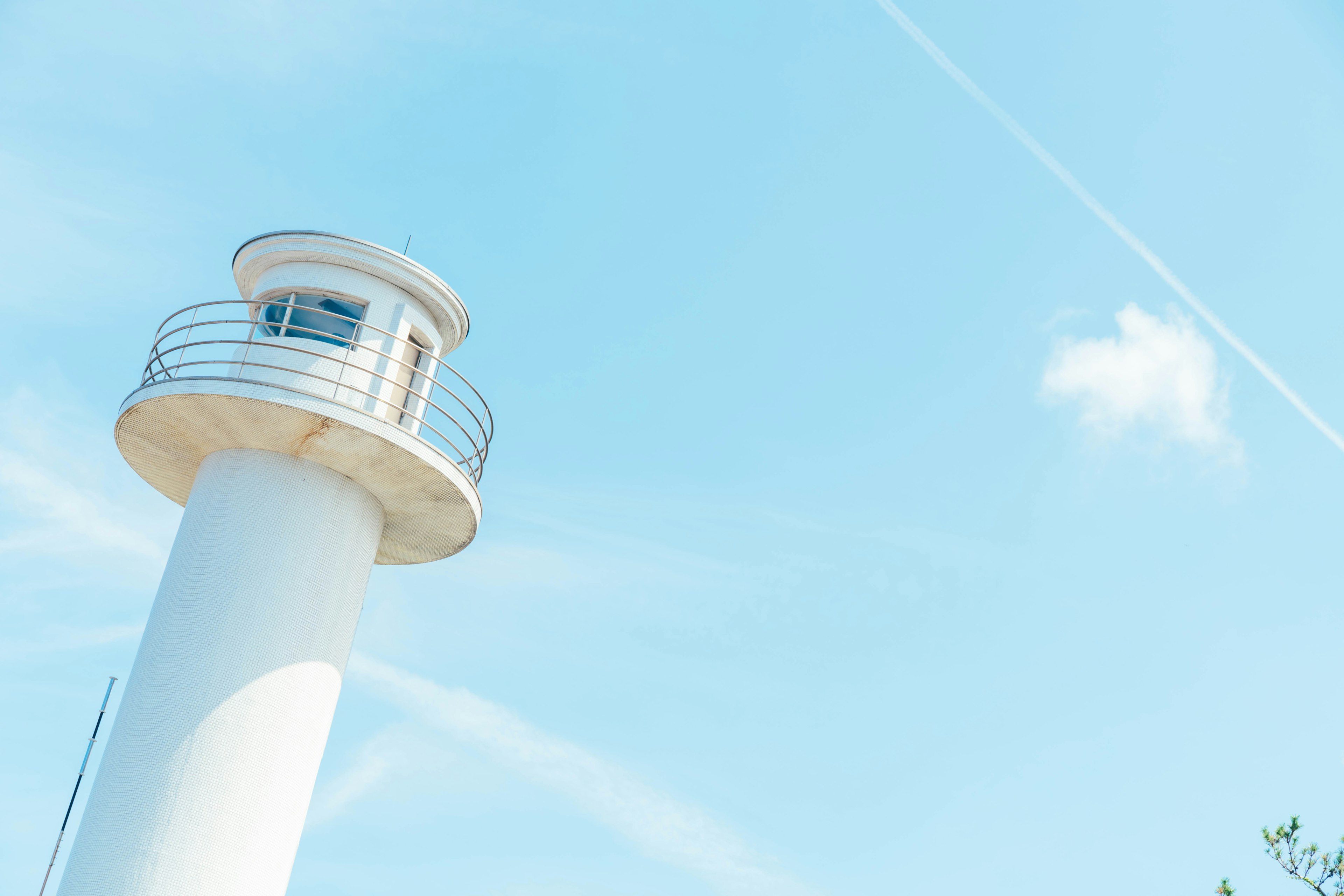 A white lighthouse under a clear blue sky