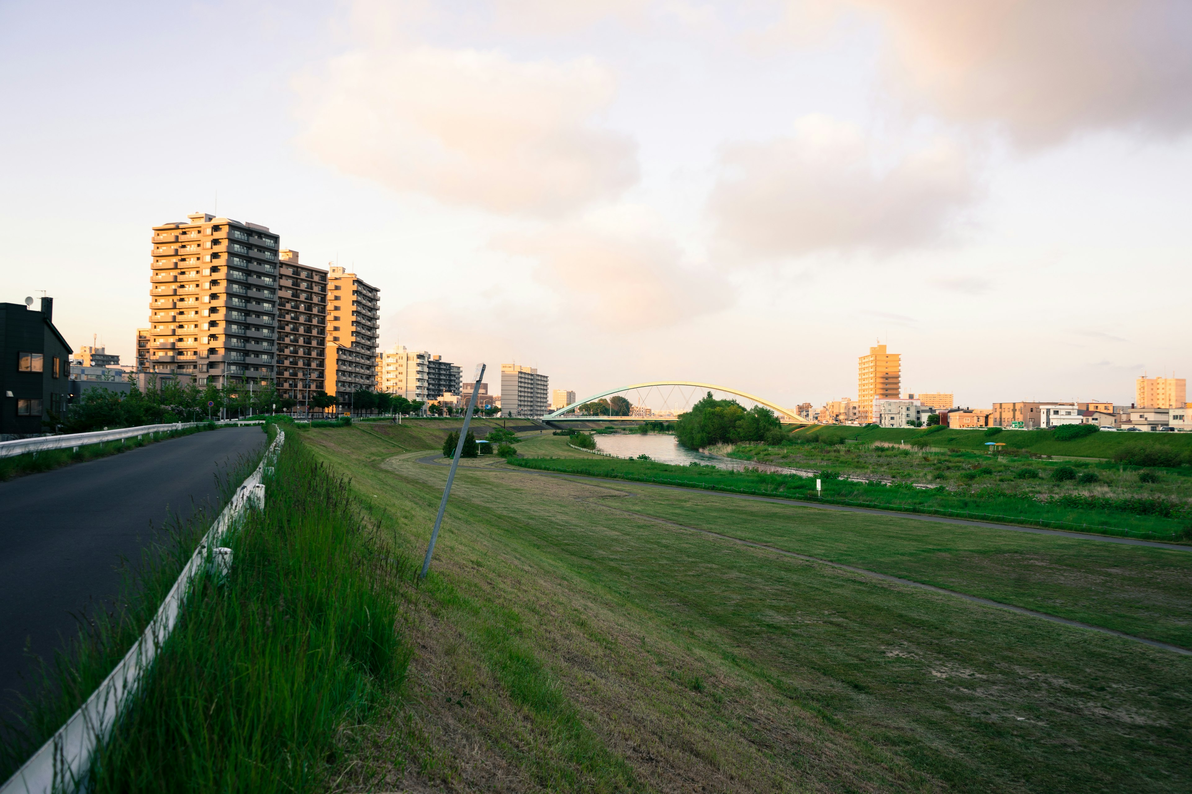 Riverbank landscape illuminated by sunset with tall buildings