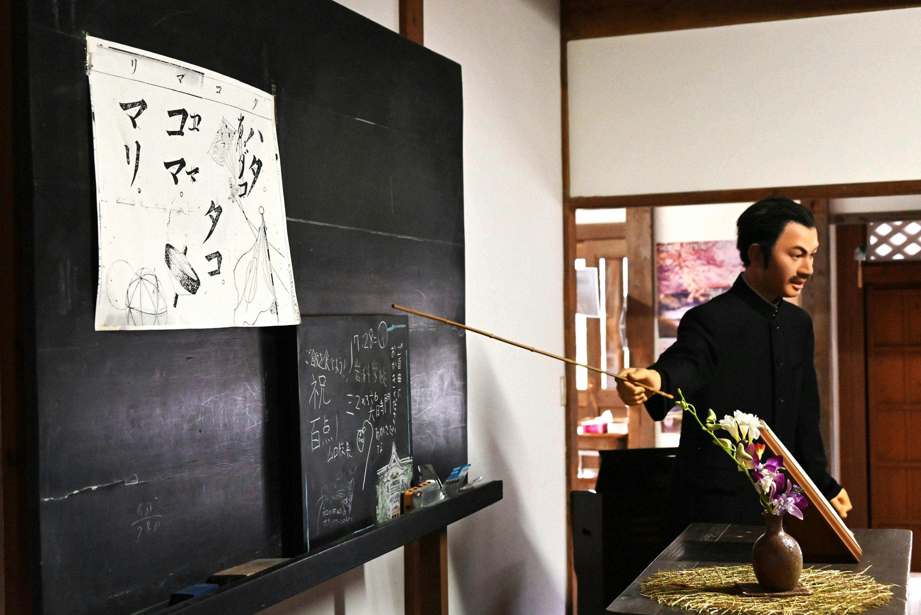 Homme donnant des instructions devant un tableau noir avec un arrangement floral