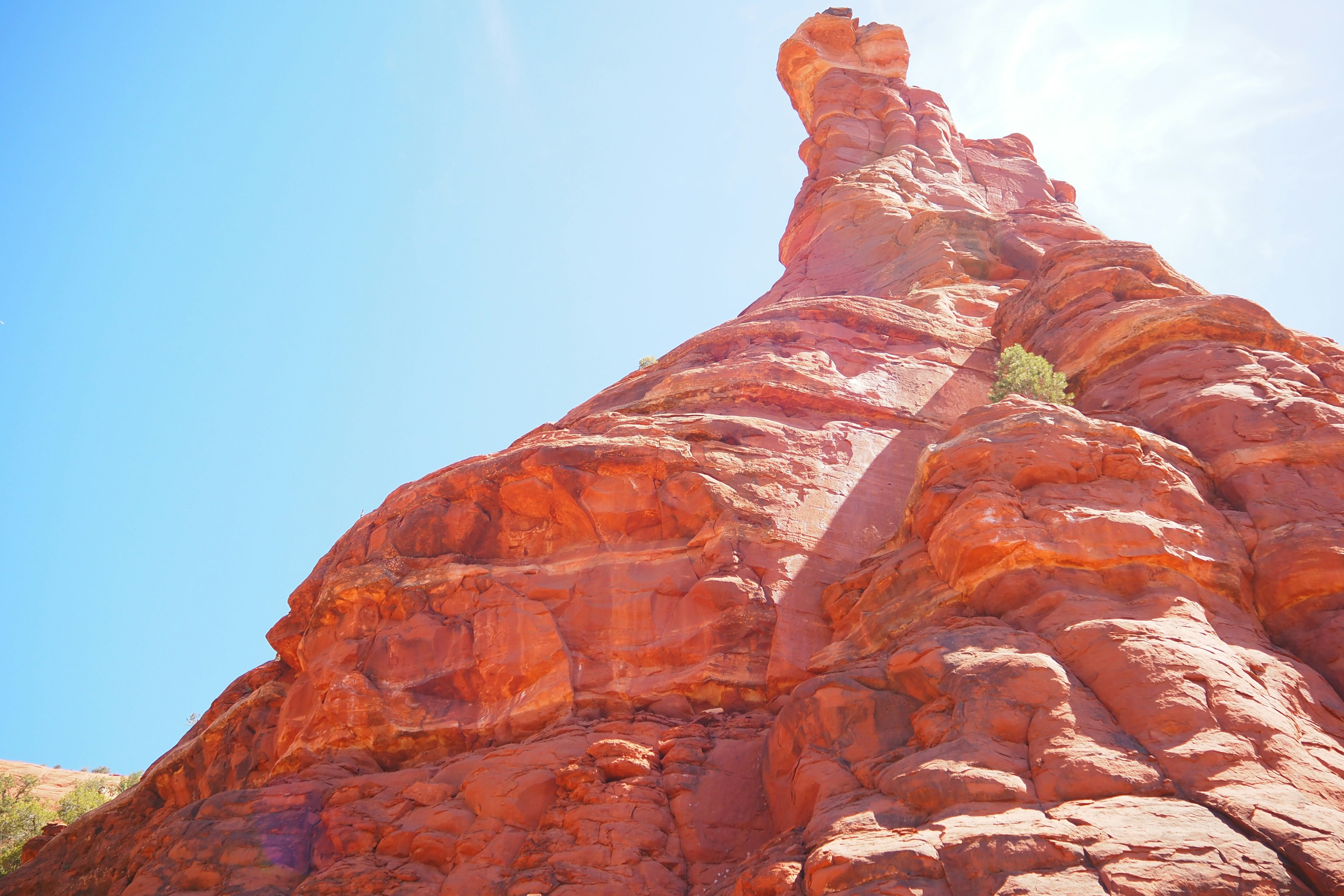 Steep red rock formation under a clear blue sky