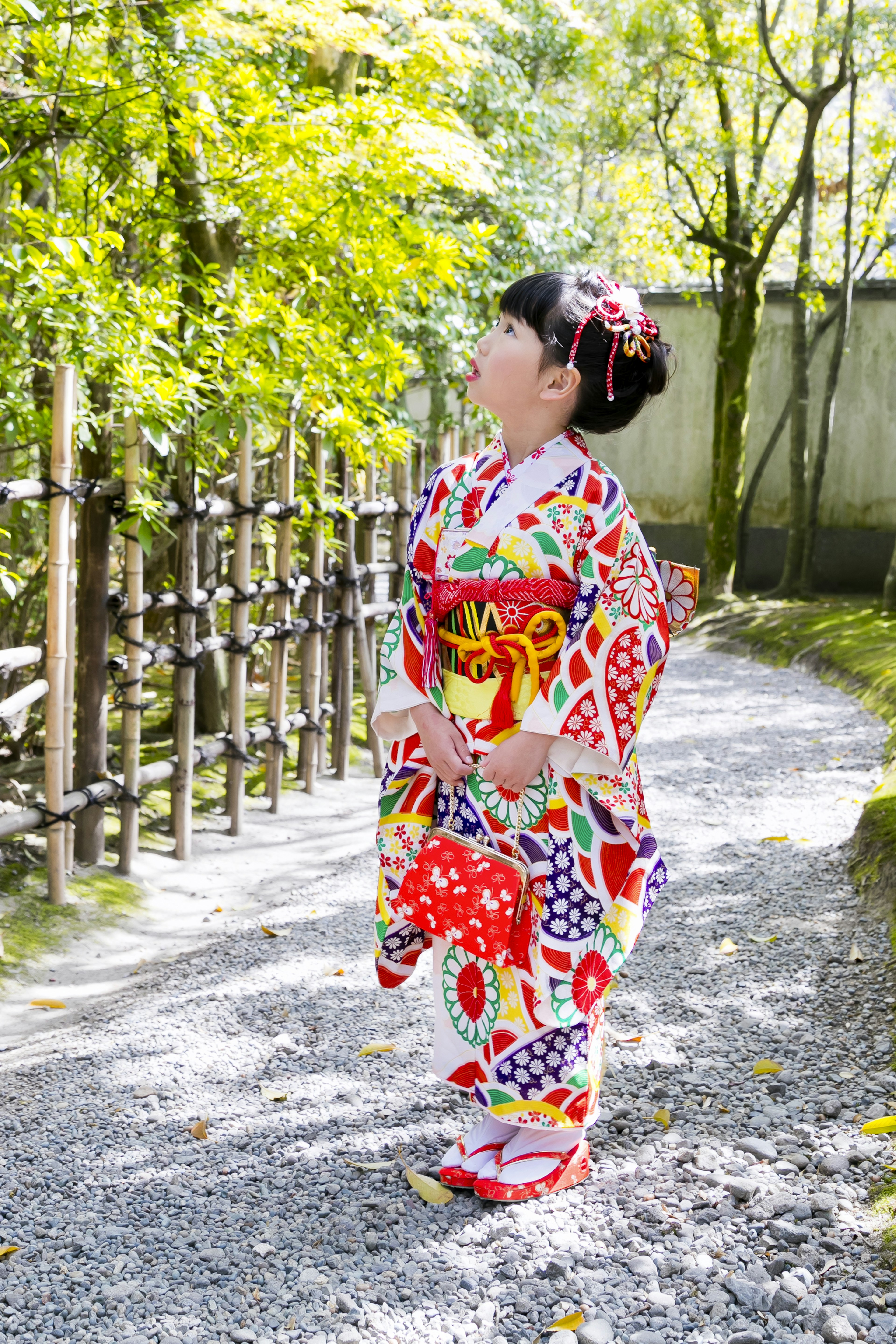 Seorang gadis mengenakan kimono berwarna-warni berdiri di lingkungan alami