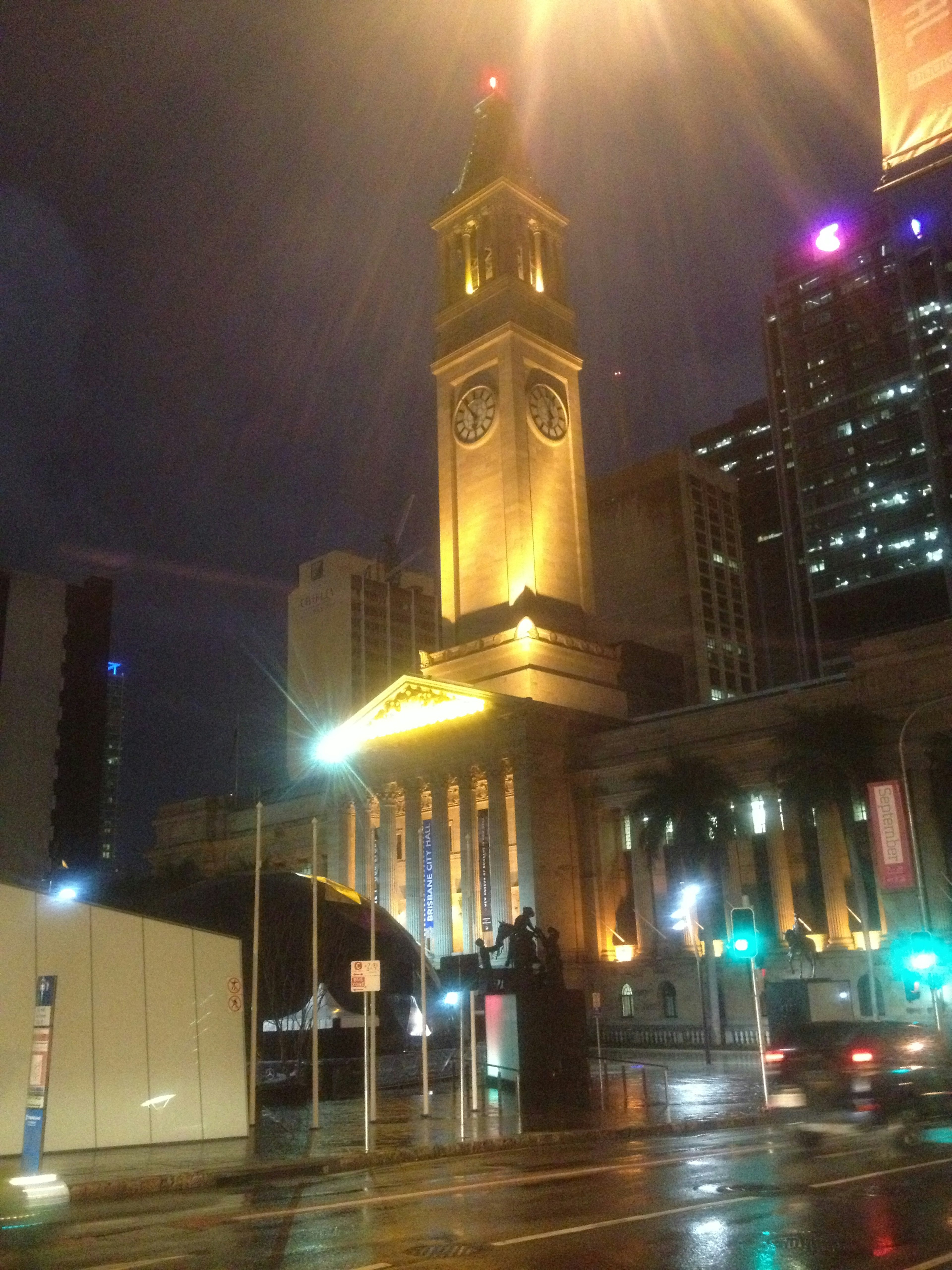 Edificio con torre dell'orologio illuminata in una scena urbana notturna