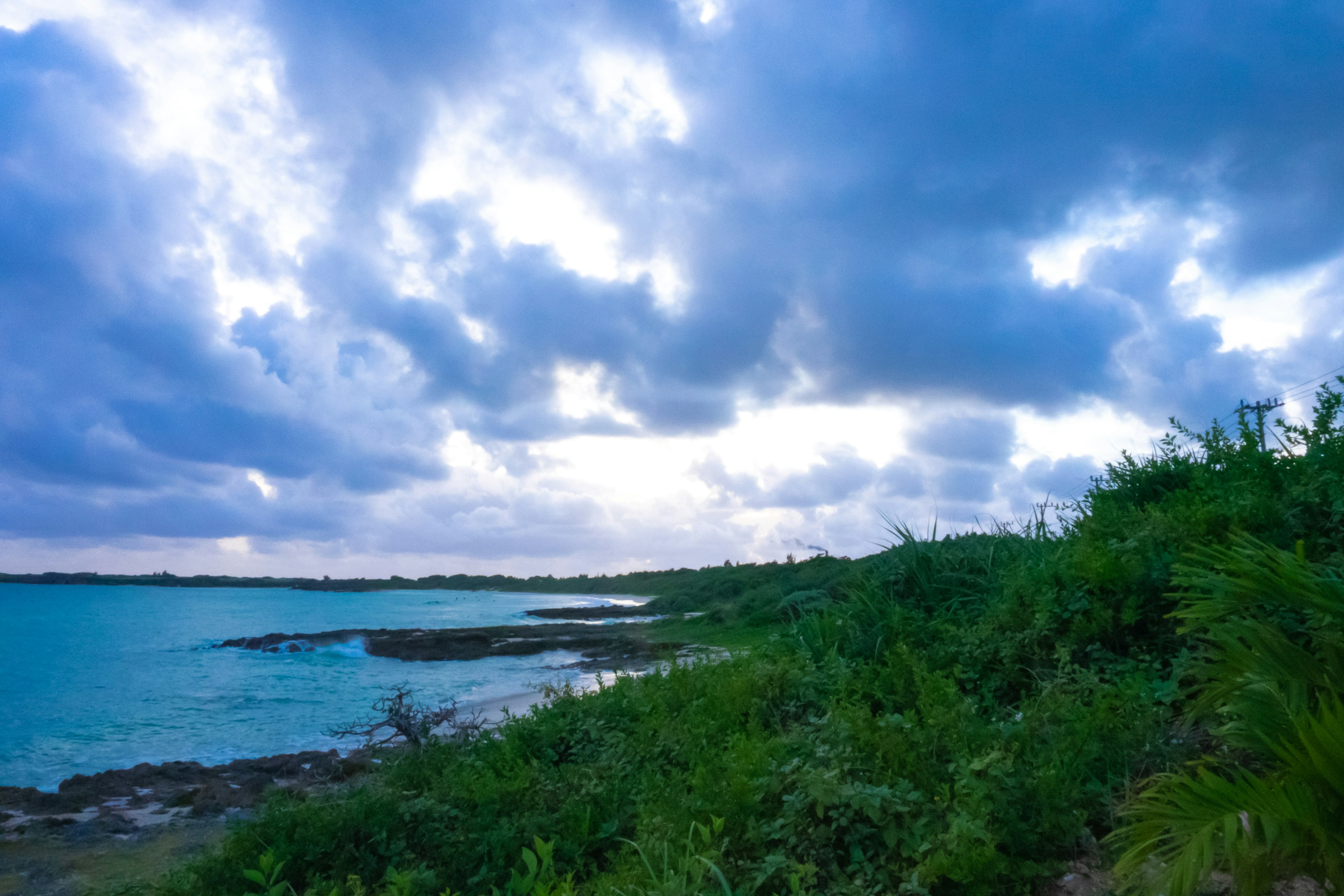 藍色海洋和茂密植被的風景，雲層覆蓋的天空