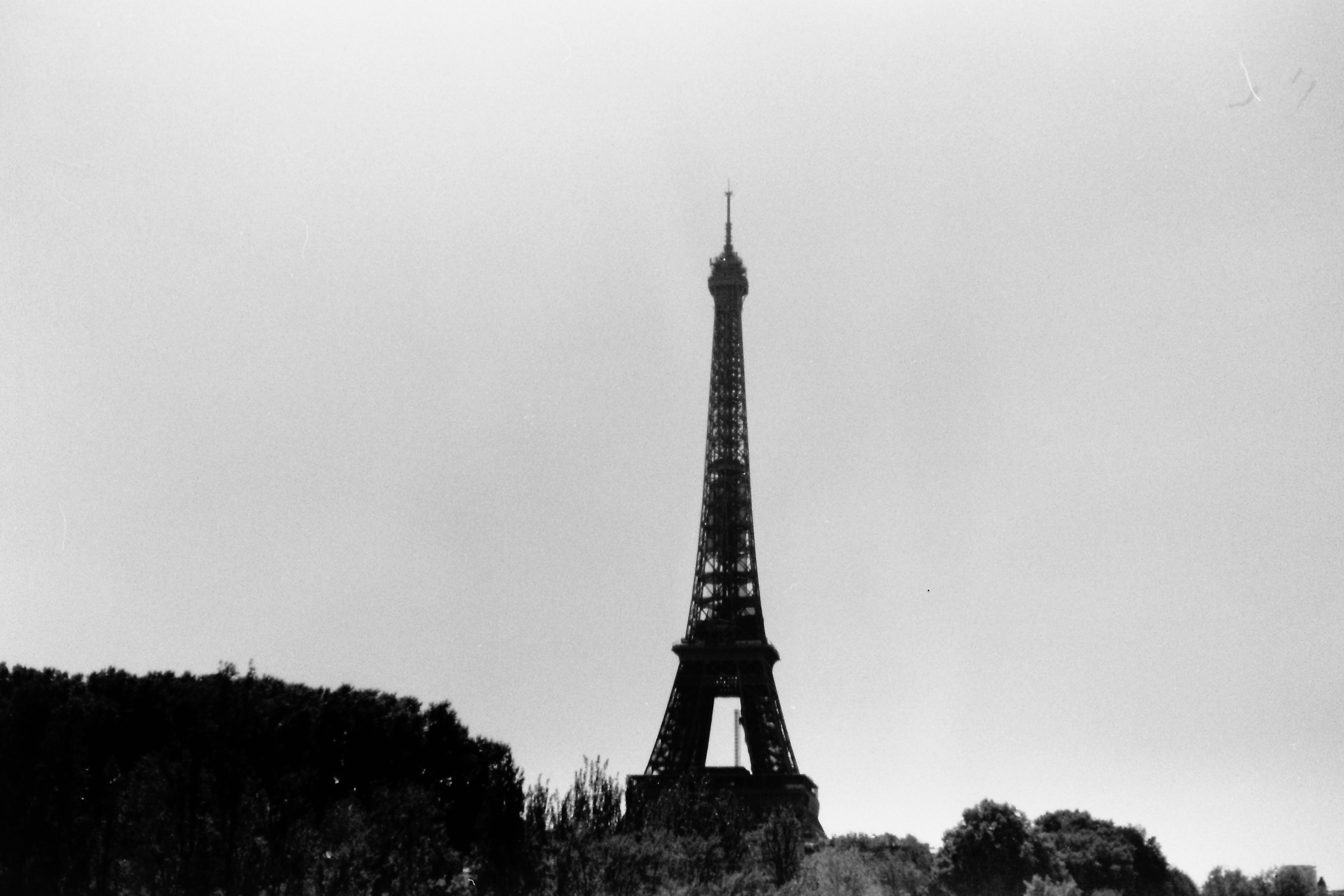 Silhouette of the Eiffel Tower against a cloudy sky in black and white