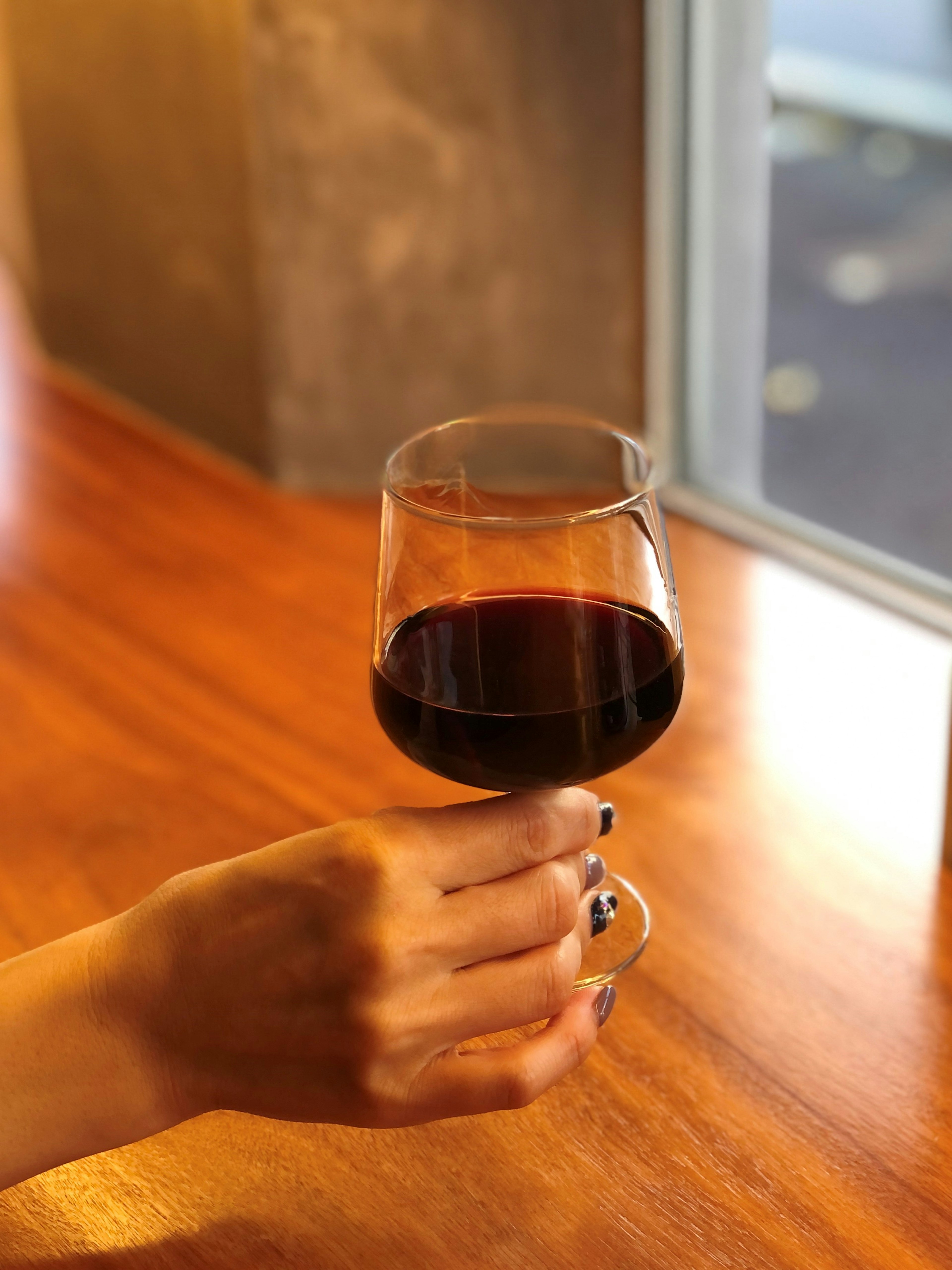 A hand holding a glass of red wine