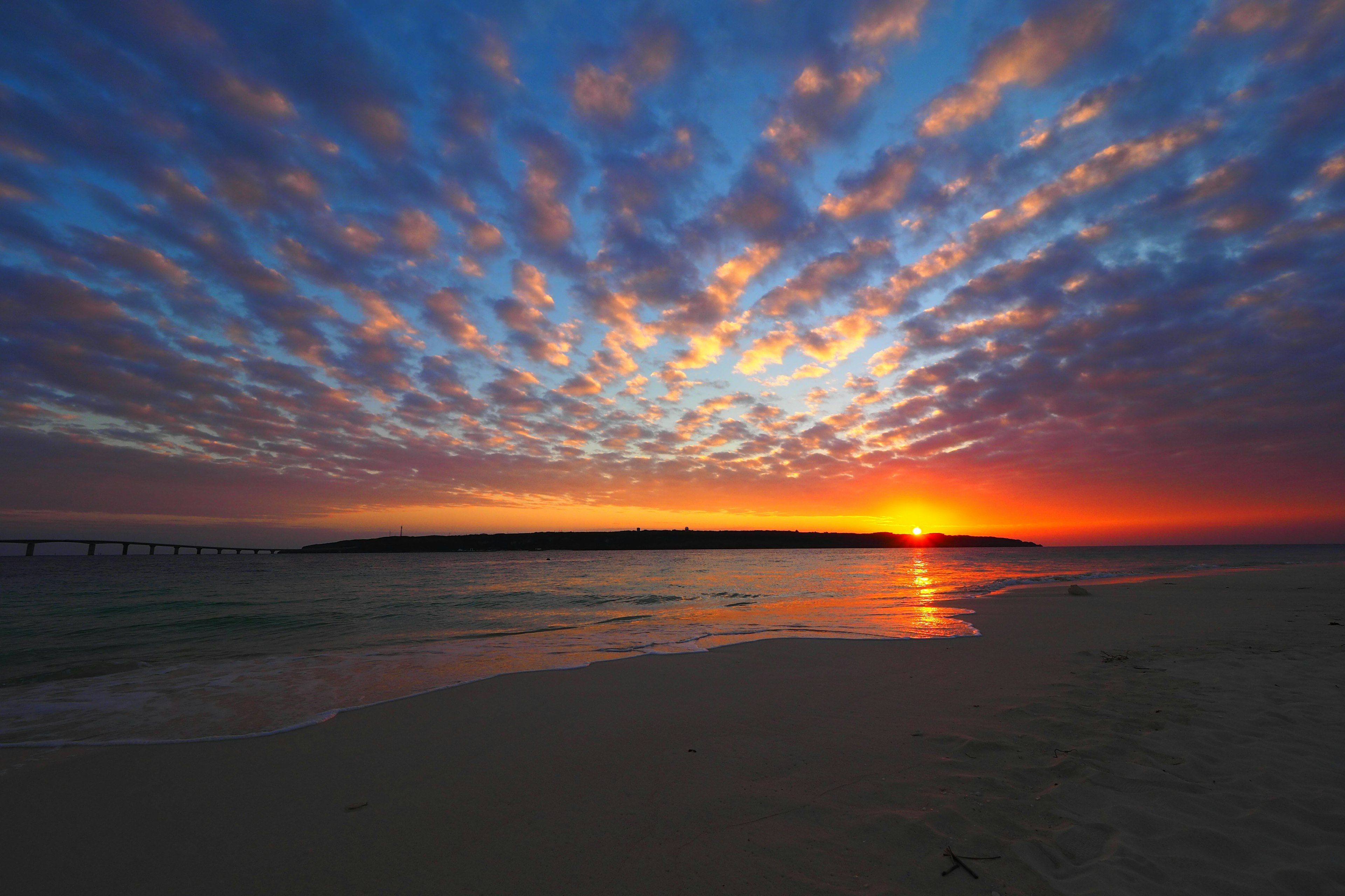 Atemberaubende Strandlandschaft mit lebhaftem Sonnenuntergang und Wolken