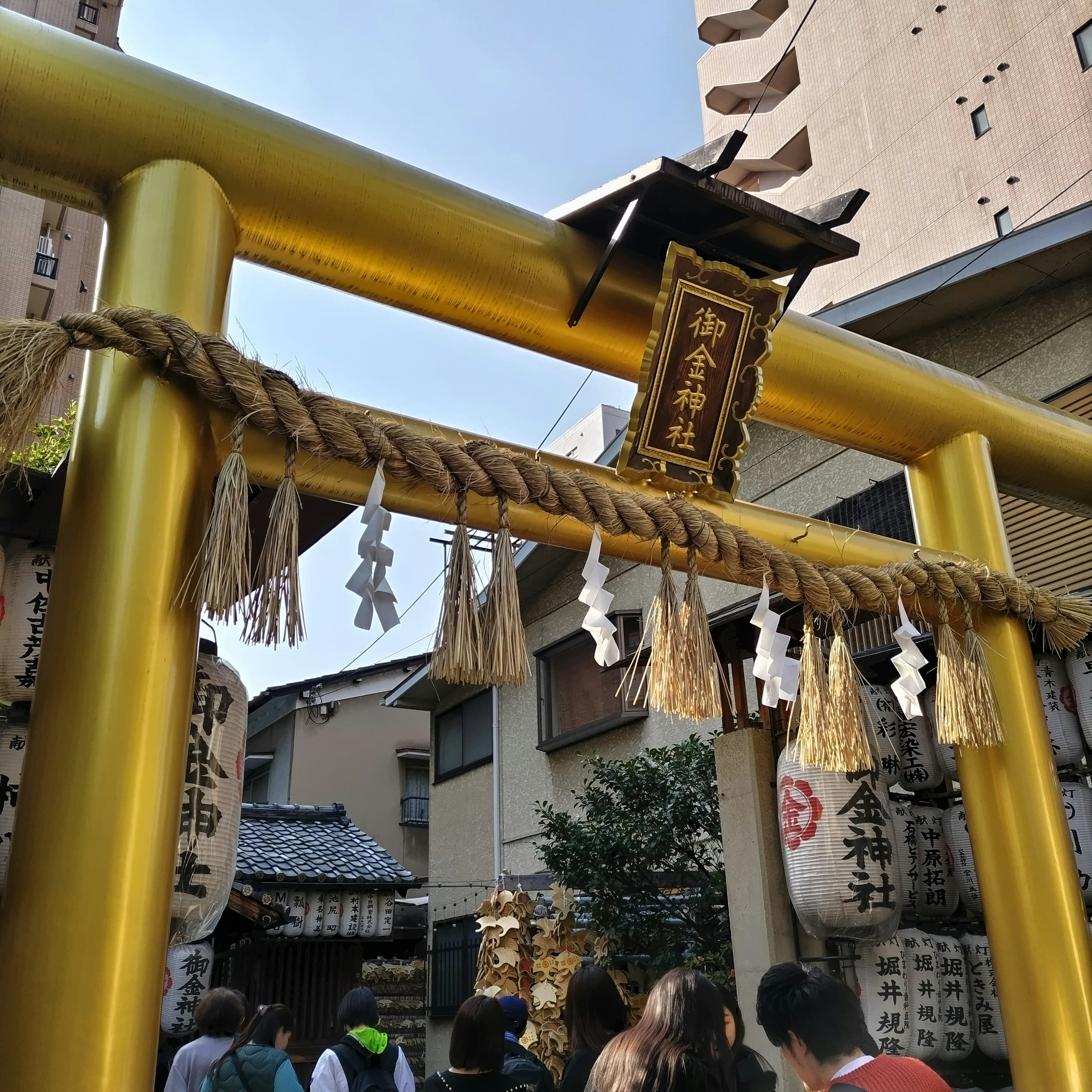 Cổng torii vàng với shimenawa tại lối vào đền thờ