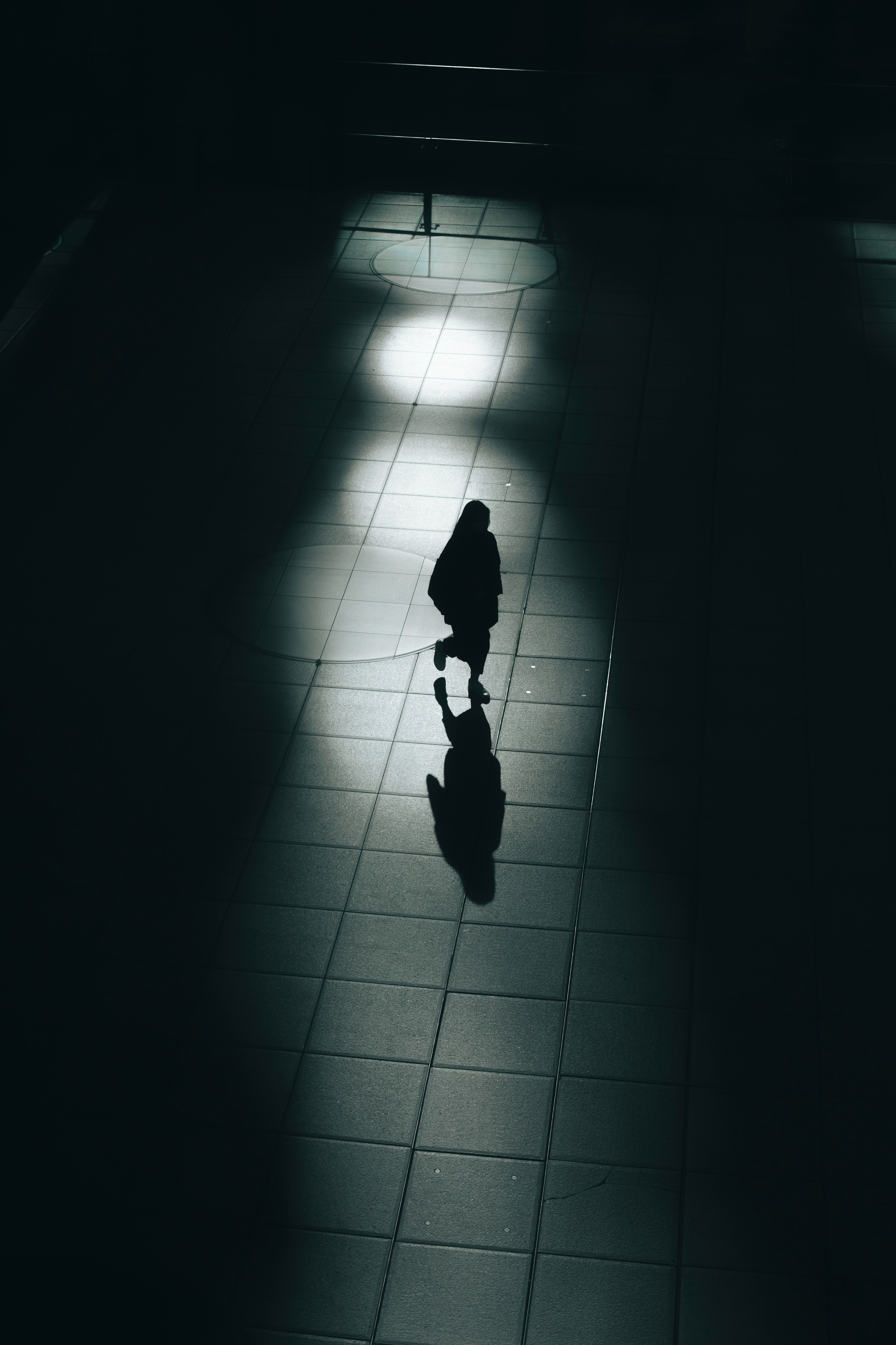 Silhouette of a person walking in a dark environment with reflected light