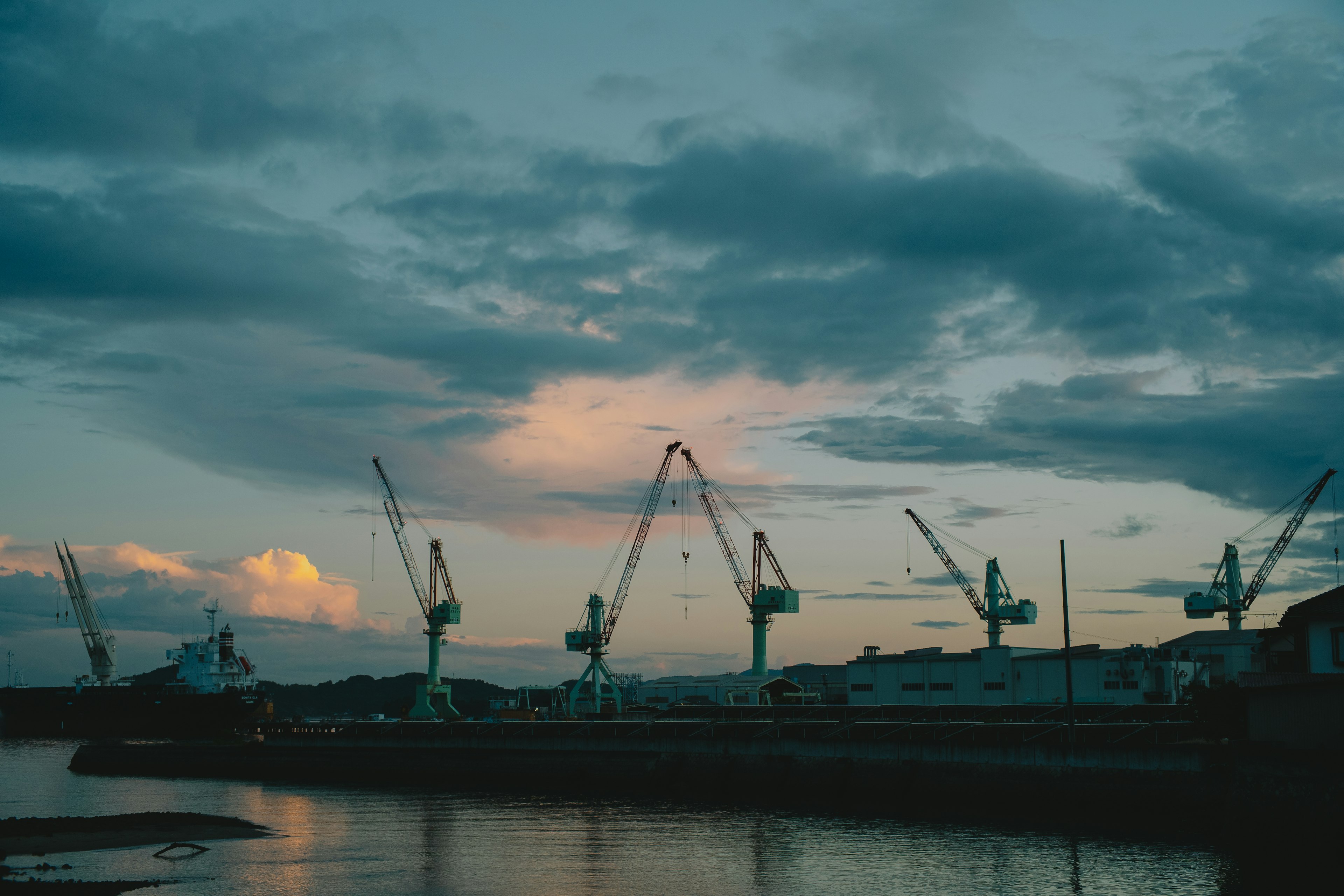 Silhouette de grues au crépuscule avec des nuages colorés dans le ciel