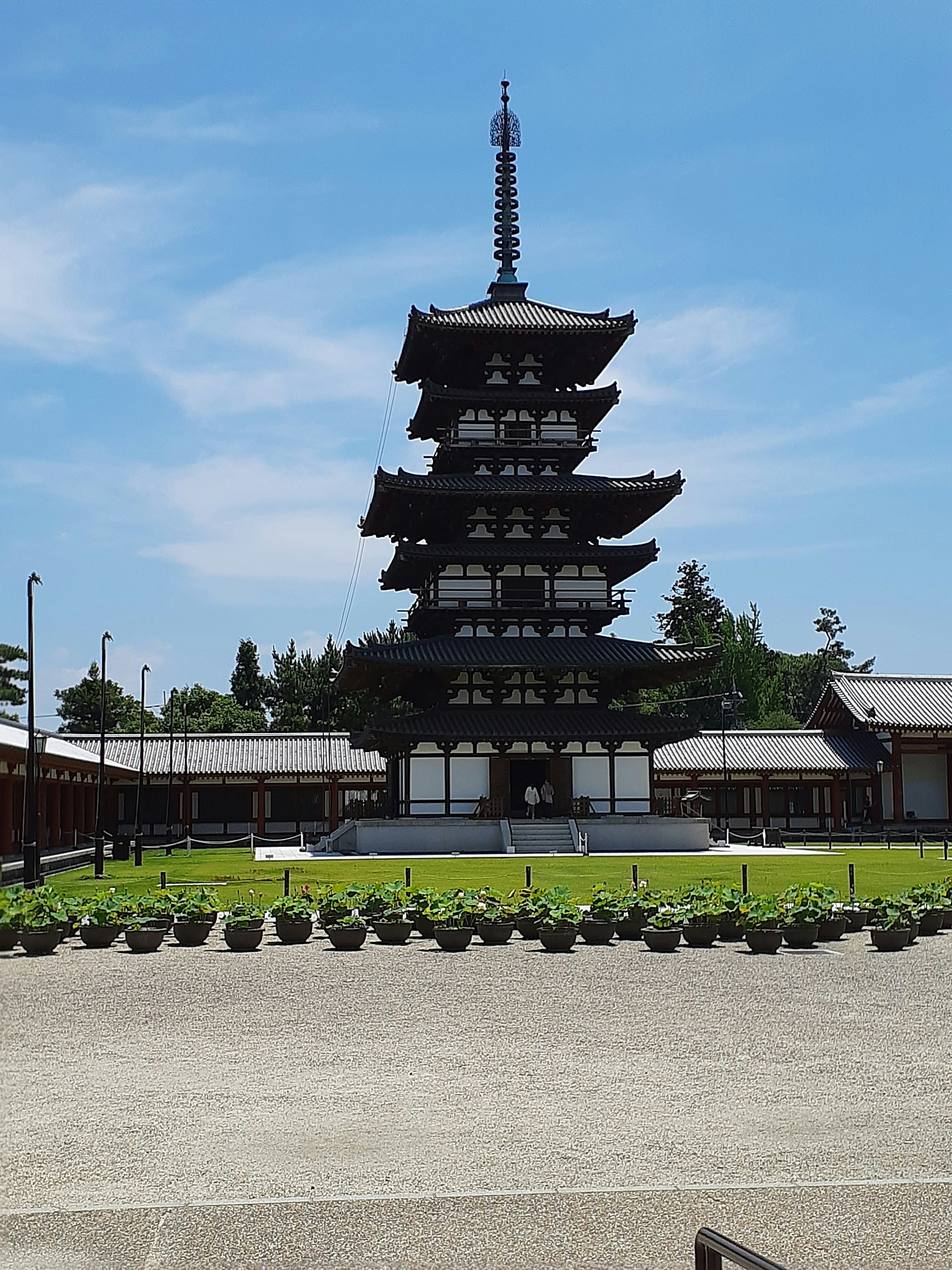 Five-story pagoda under a blue sky with surrounding garden