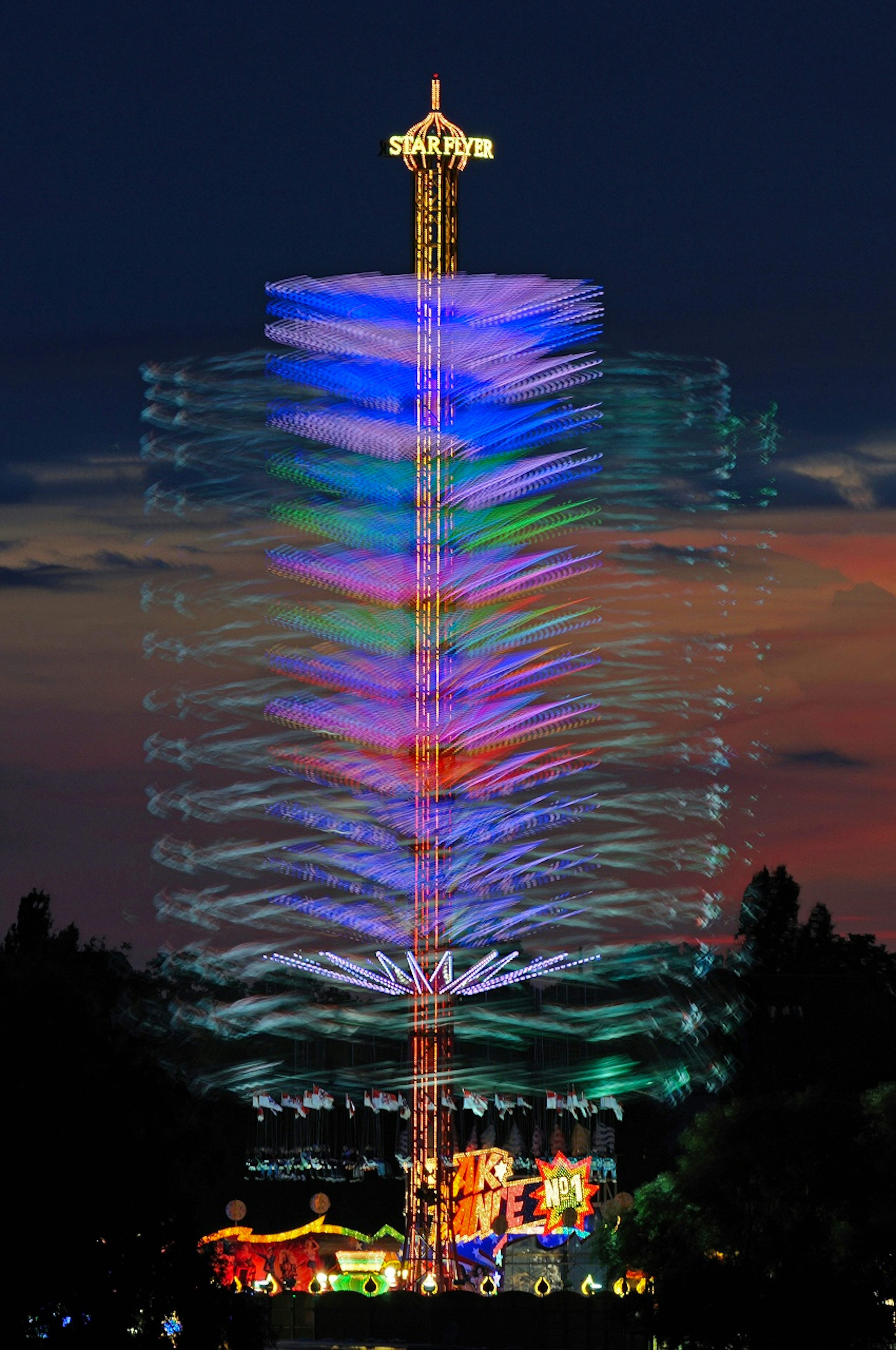 Tracce luminose colorate di una torre di parco divertimenti nel cielo notturno