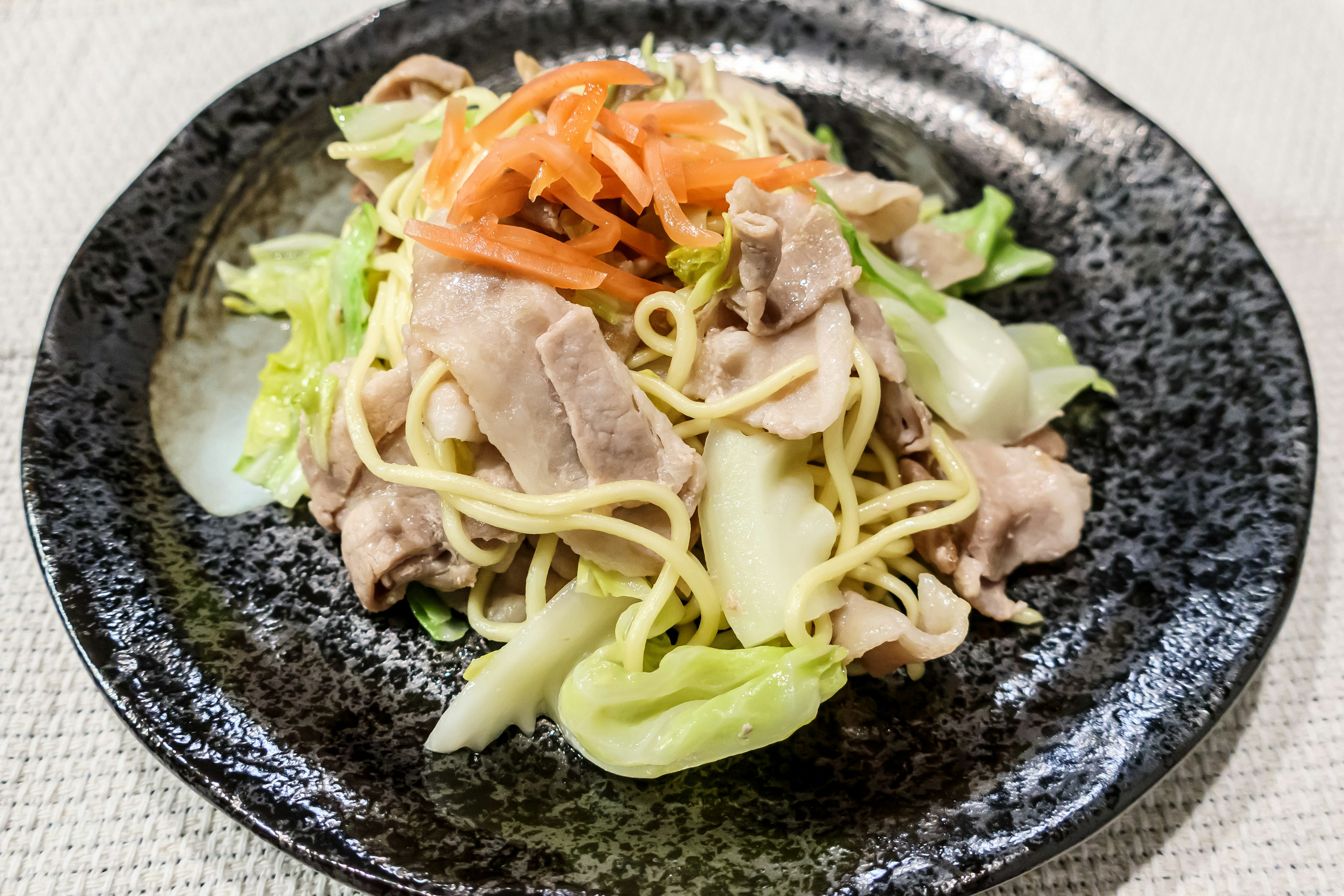 Stir-fried pork and vegetables served on a black plate