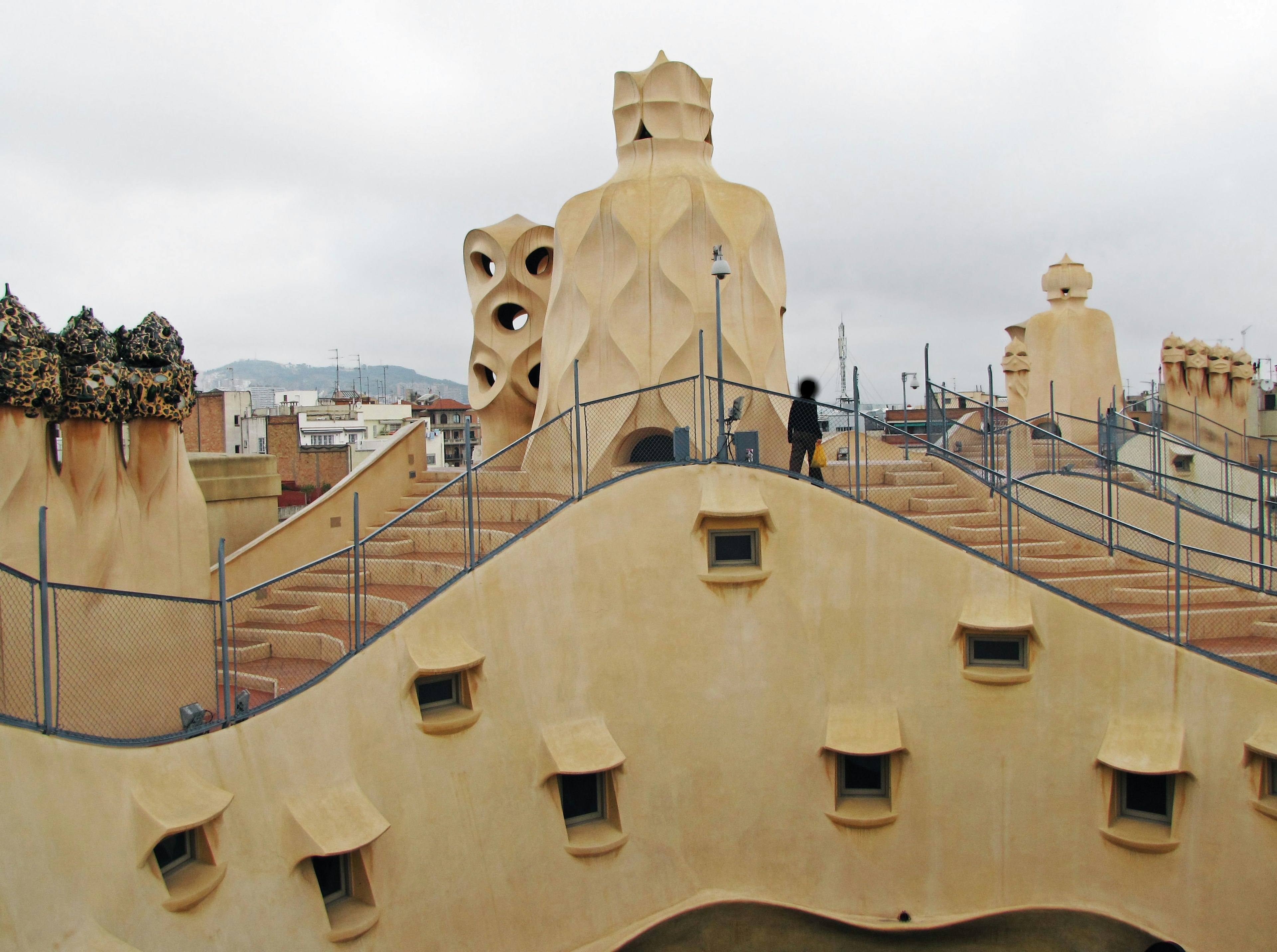 คนยืนอยู่บนหลังคาของ Casa Milà พร้อมกับประติมากรรมปล่องไฟที่ไม่เหมือนใคร