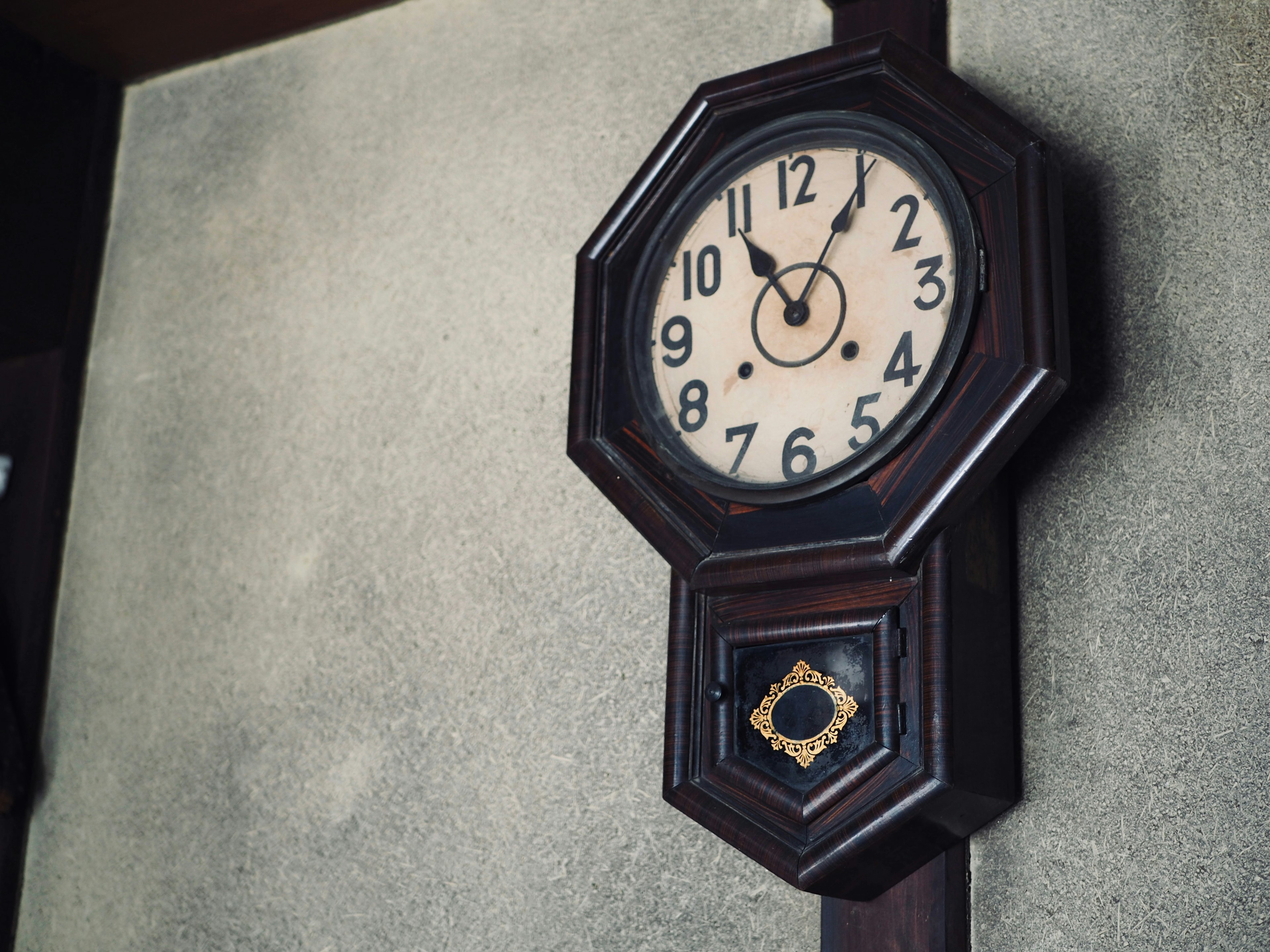 Reloj de pared antiguo de madera con forma octagonal y esfera clásica