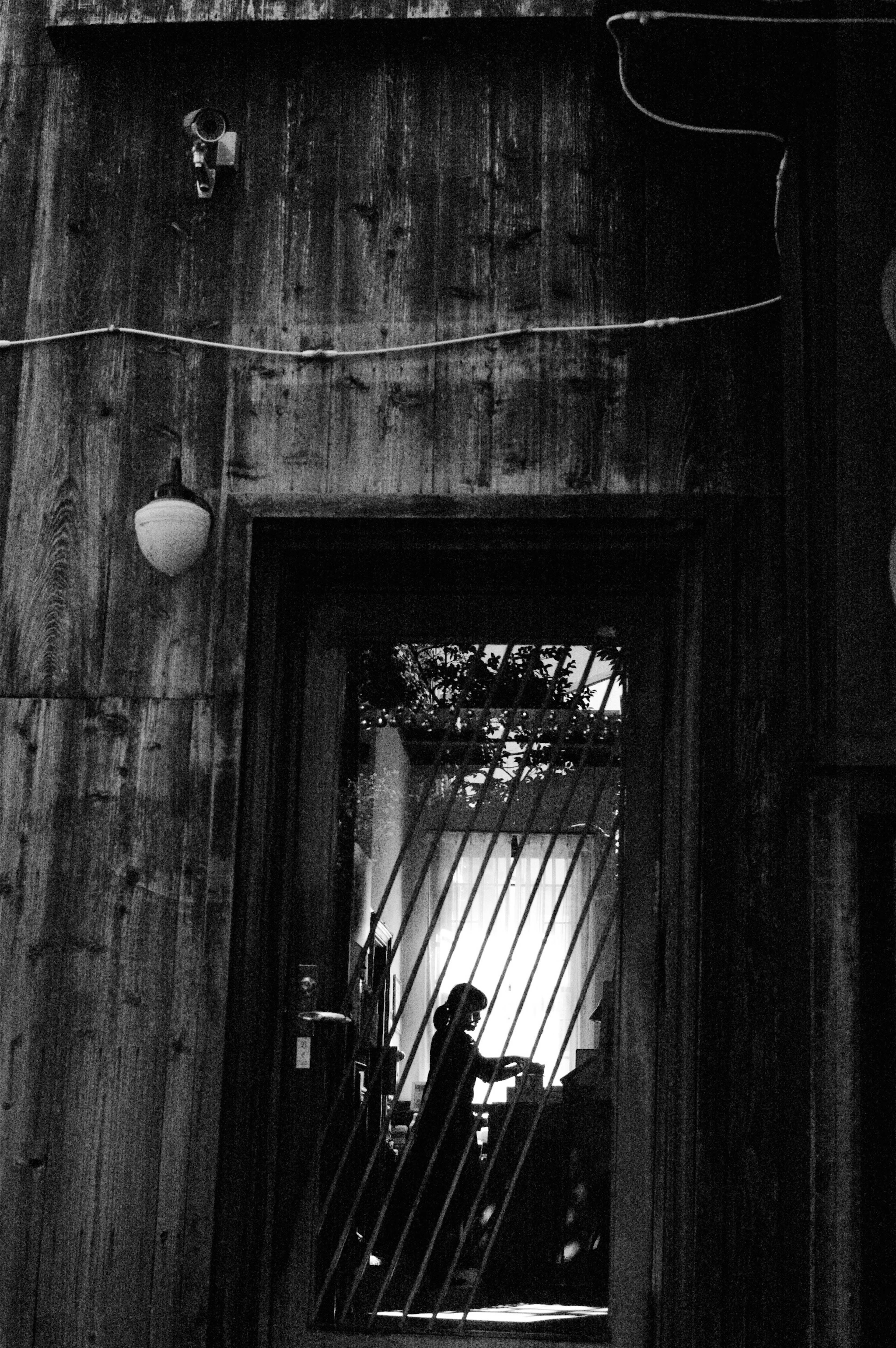 Silhouette and shadows visible through a wooden door frame