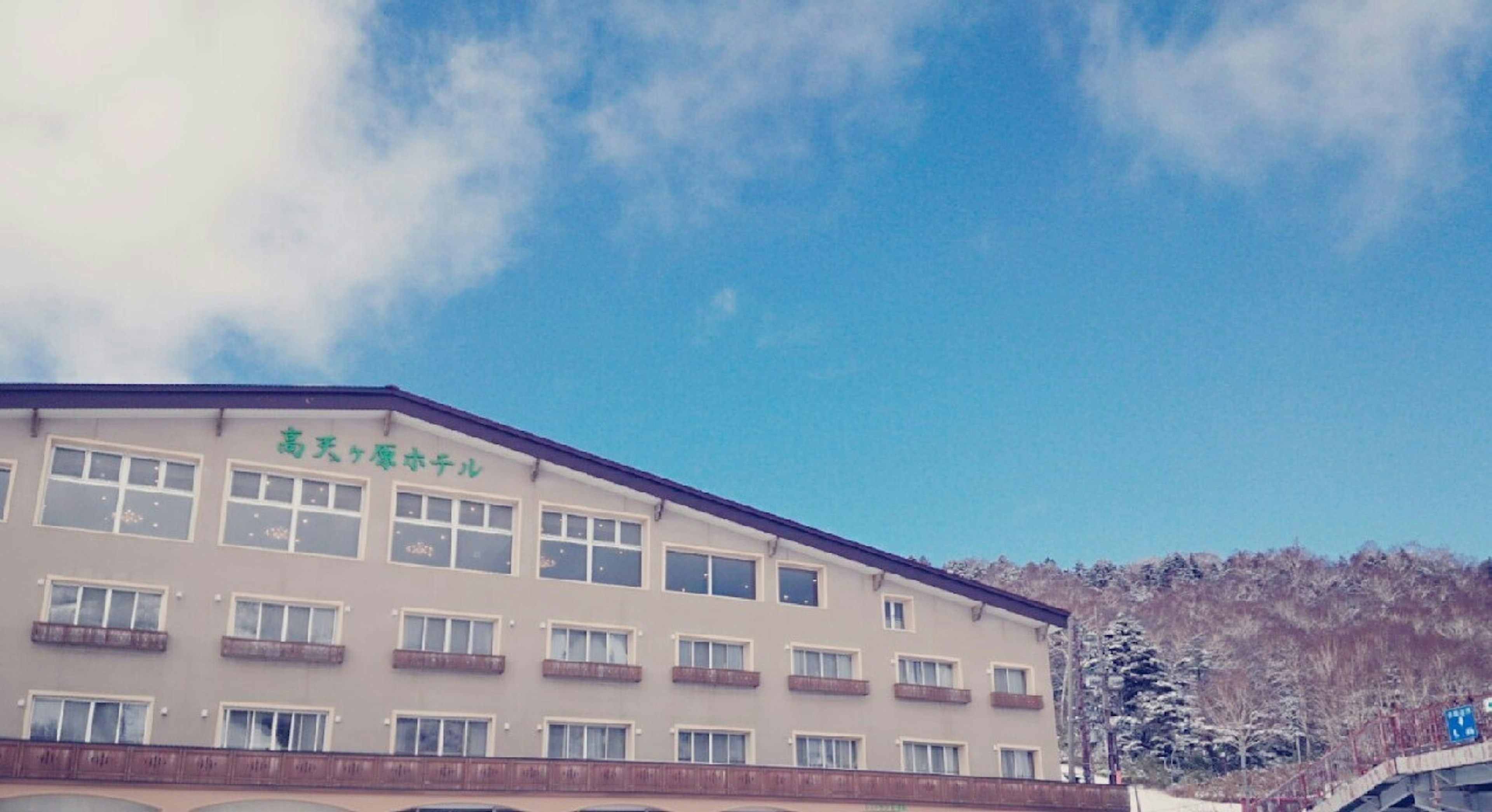 青い空の下にある宿泊施設の外観と山の風景