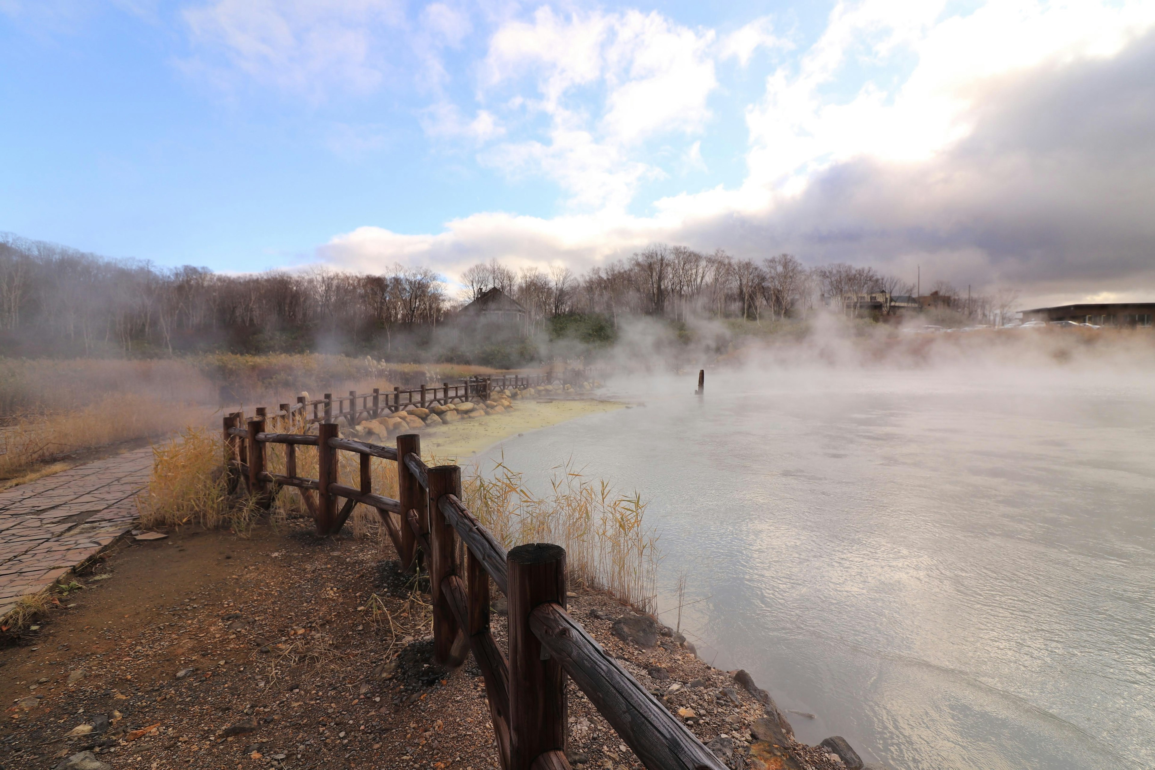 Paisaje sereno con vapor que se eleva de las aguas termales y cerca de madera