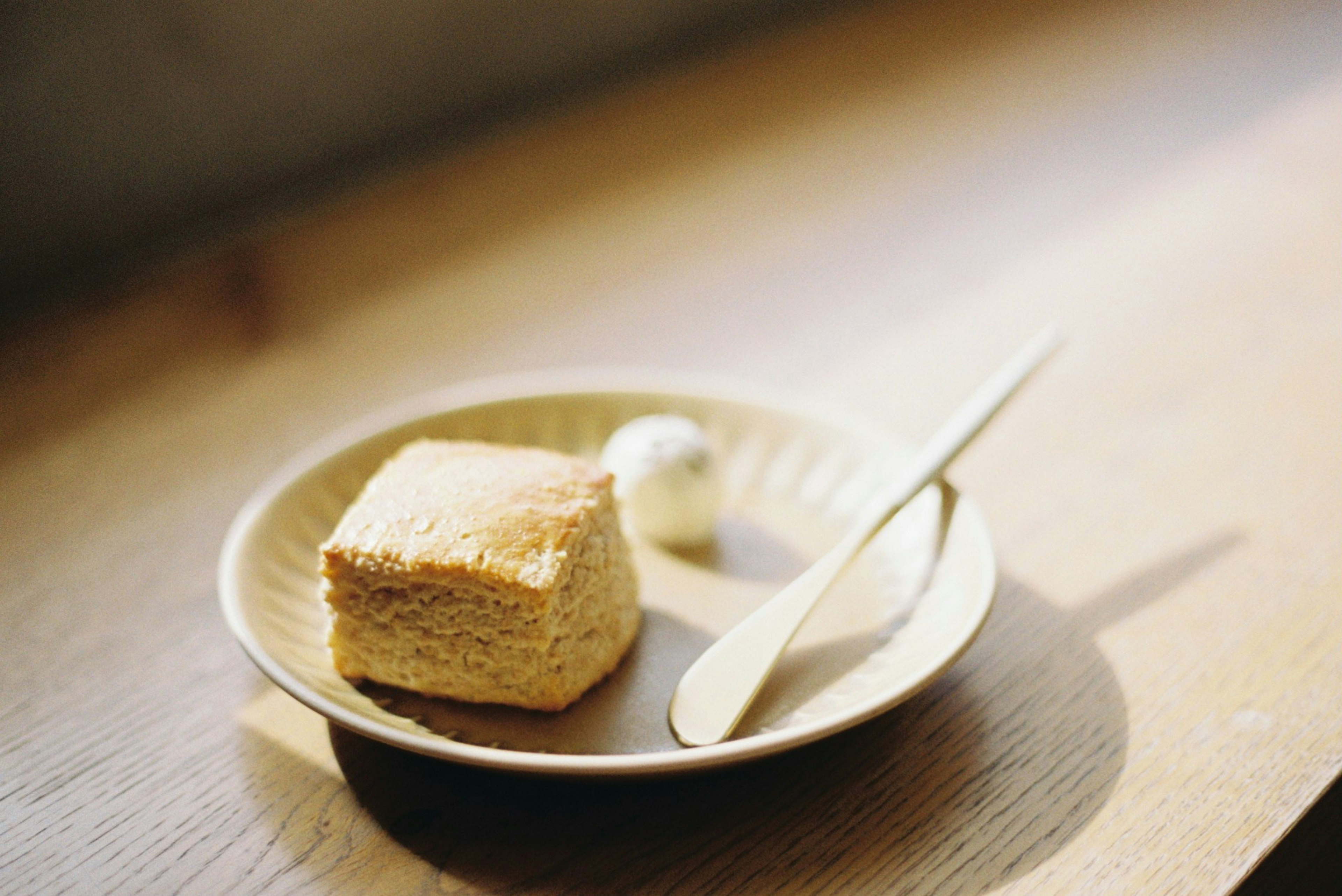 A slice of cake on a plate with a scoop of ice cream and a spoon