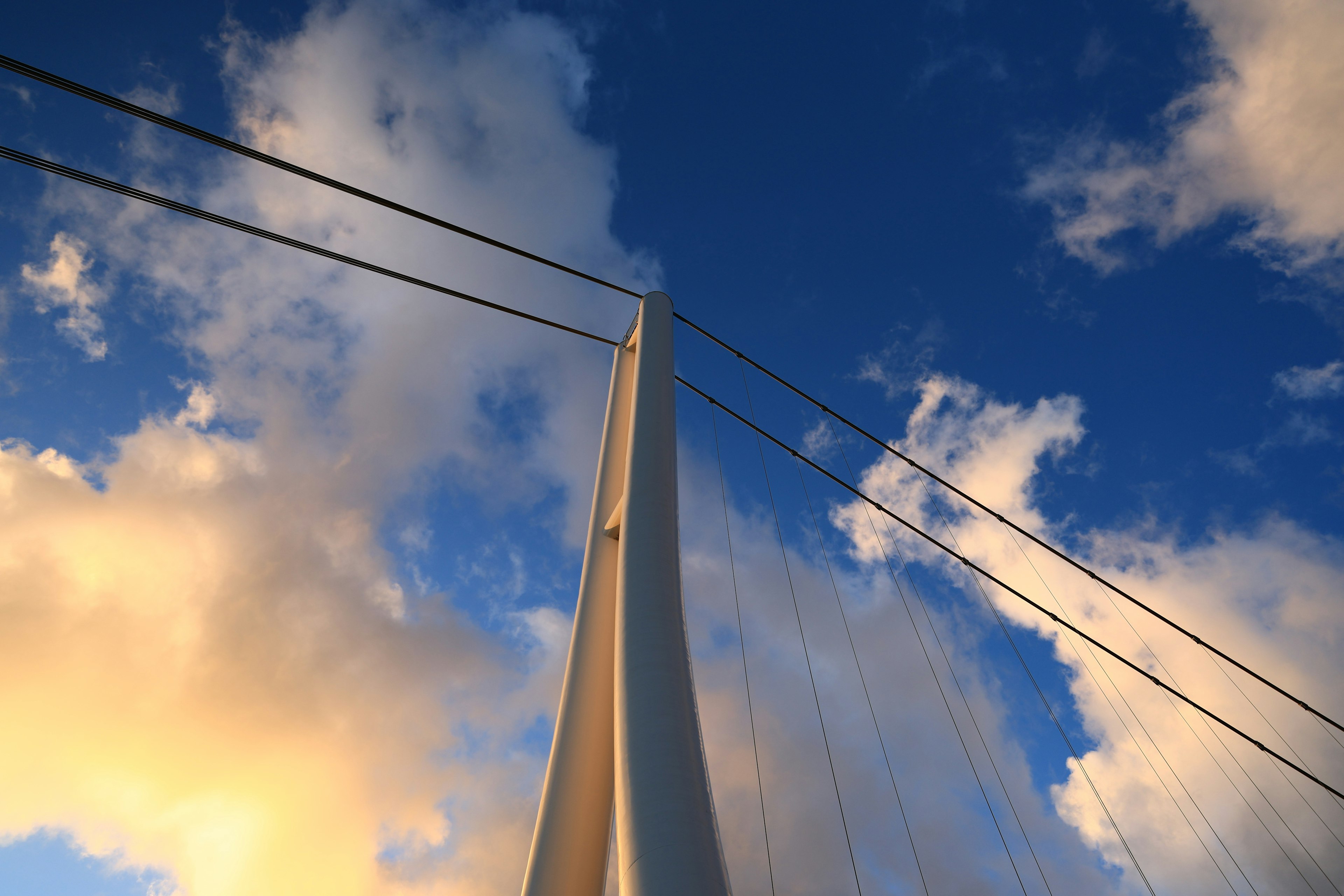 Menara jembatan yang menjulang di bawah awan indah dan langit biru