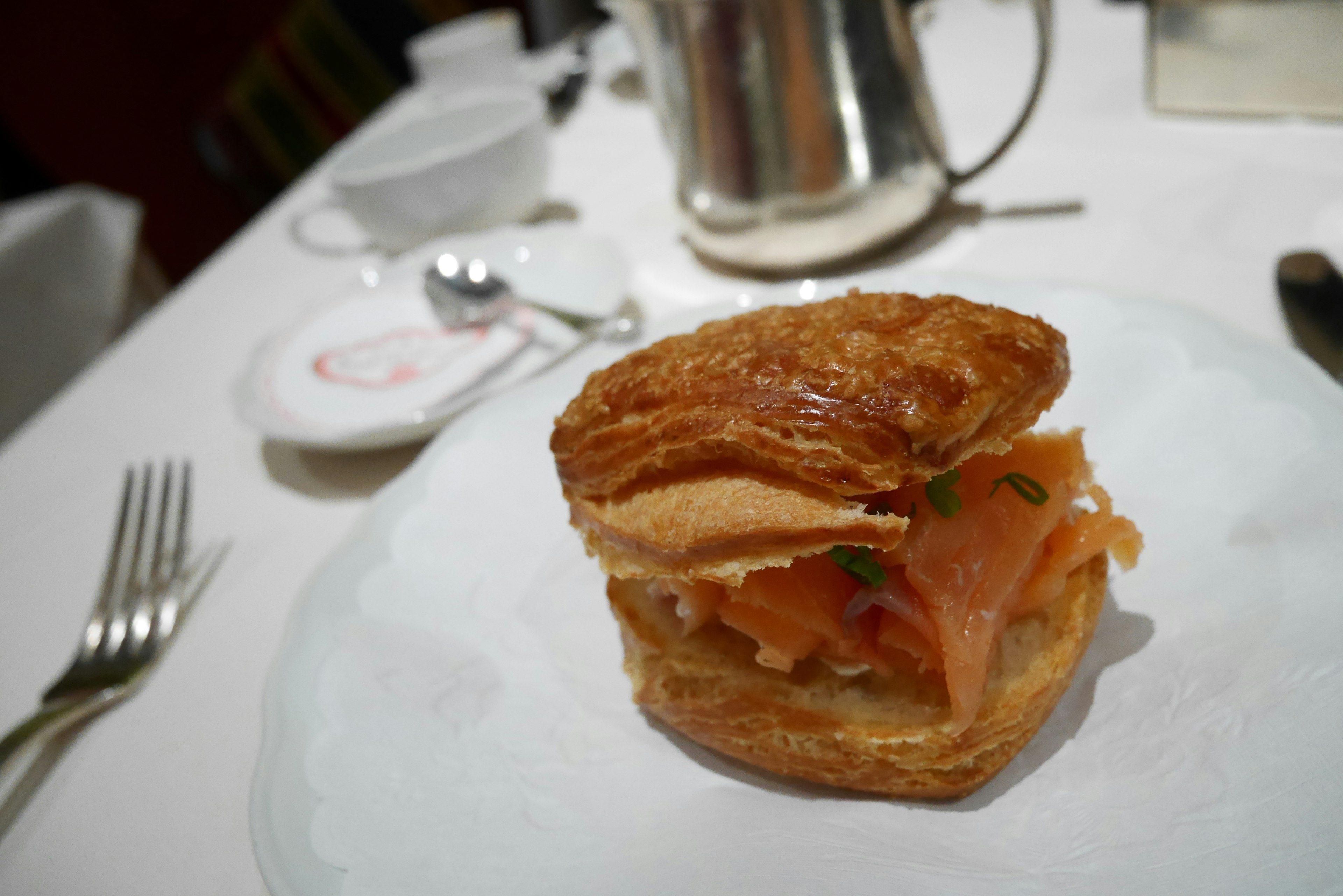 Sándwich de masa hojaldrada relleno de salmón y hierbas servido en un plato