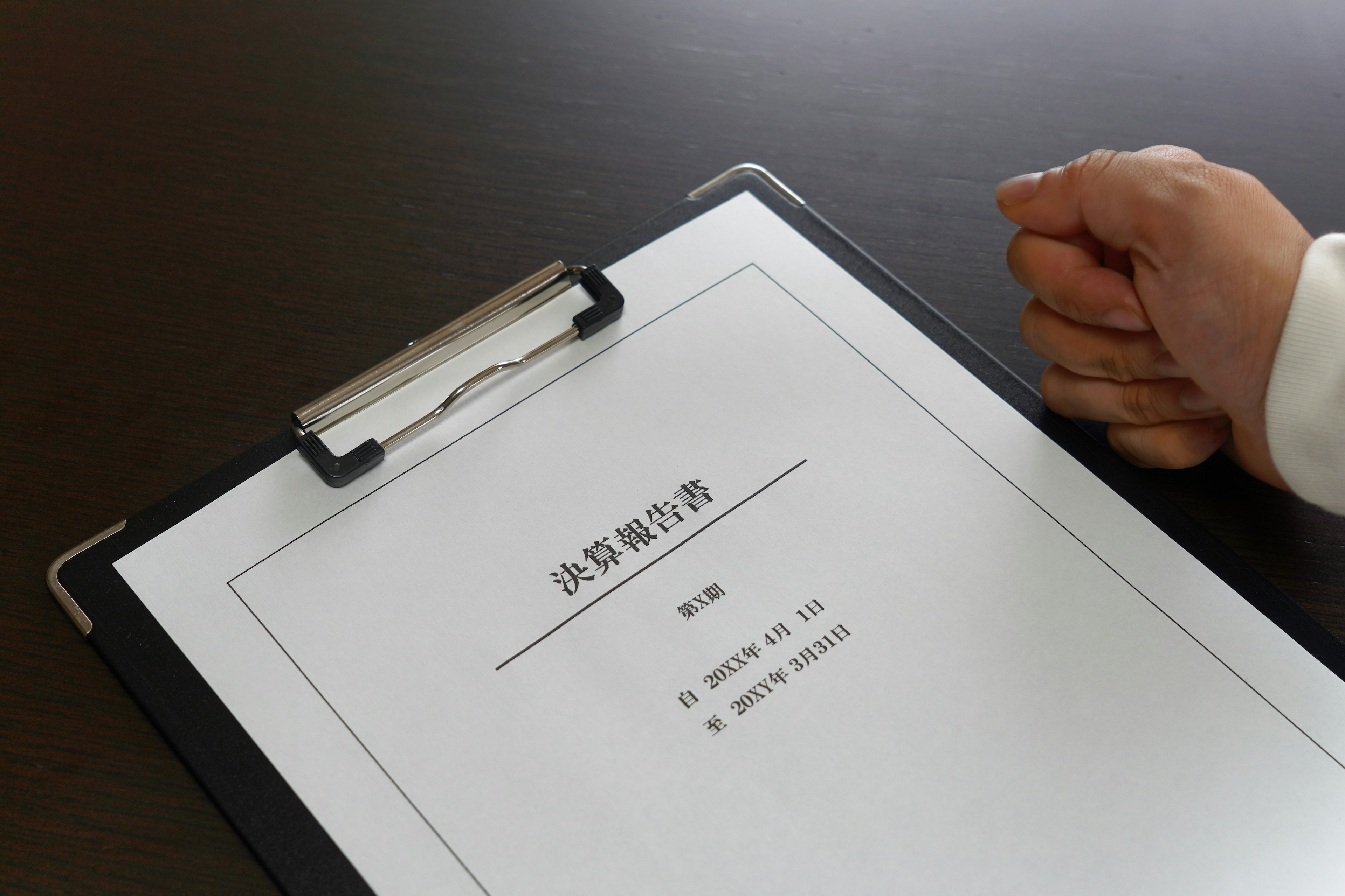 A hand resting on a clipboard with a document