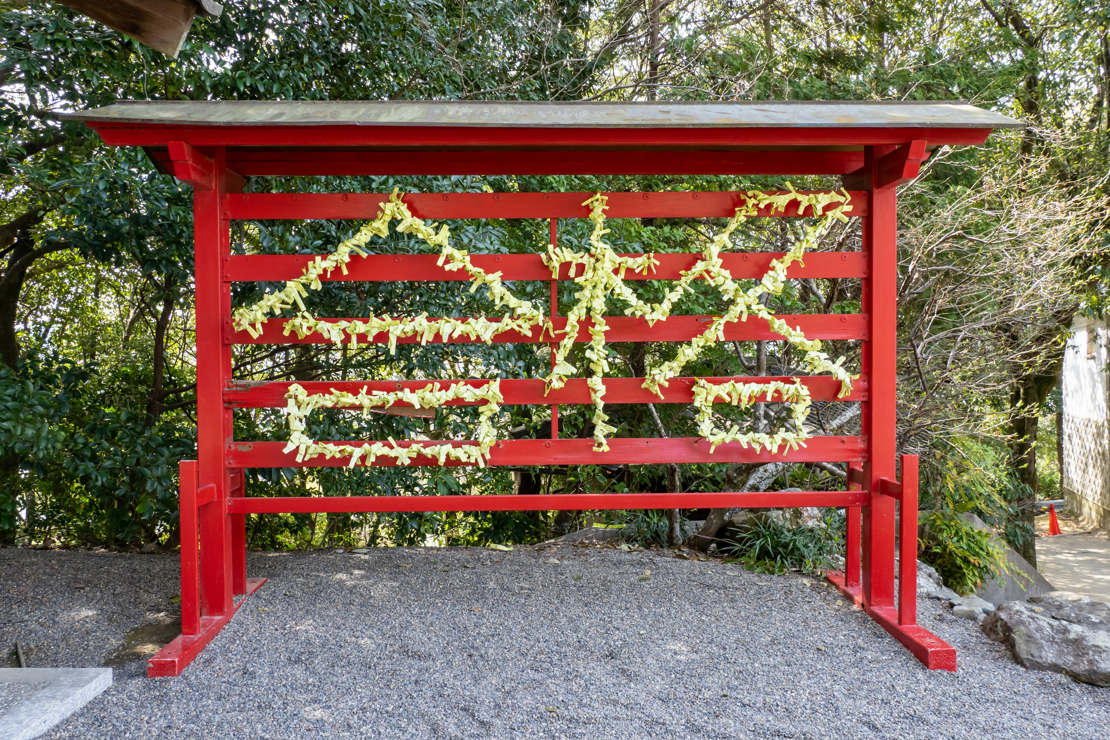 Rotes Torii geschmückt mit gelben Blumen und Inschriften