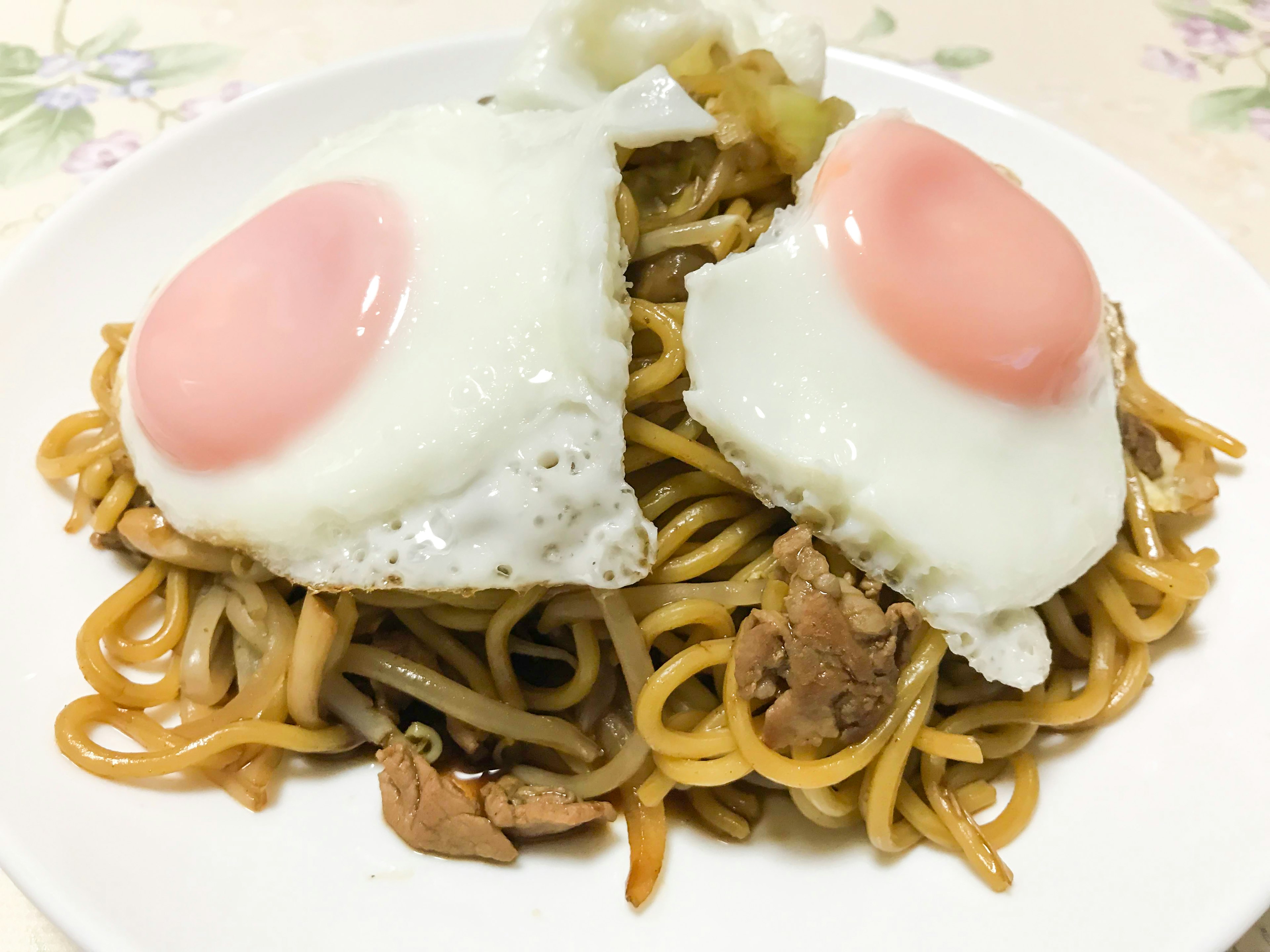 Assiette de nouilles sautées garnie d'œufs au plat