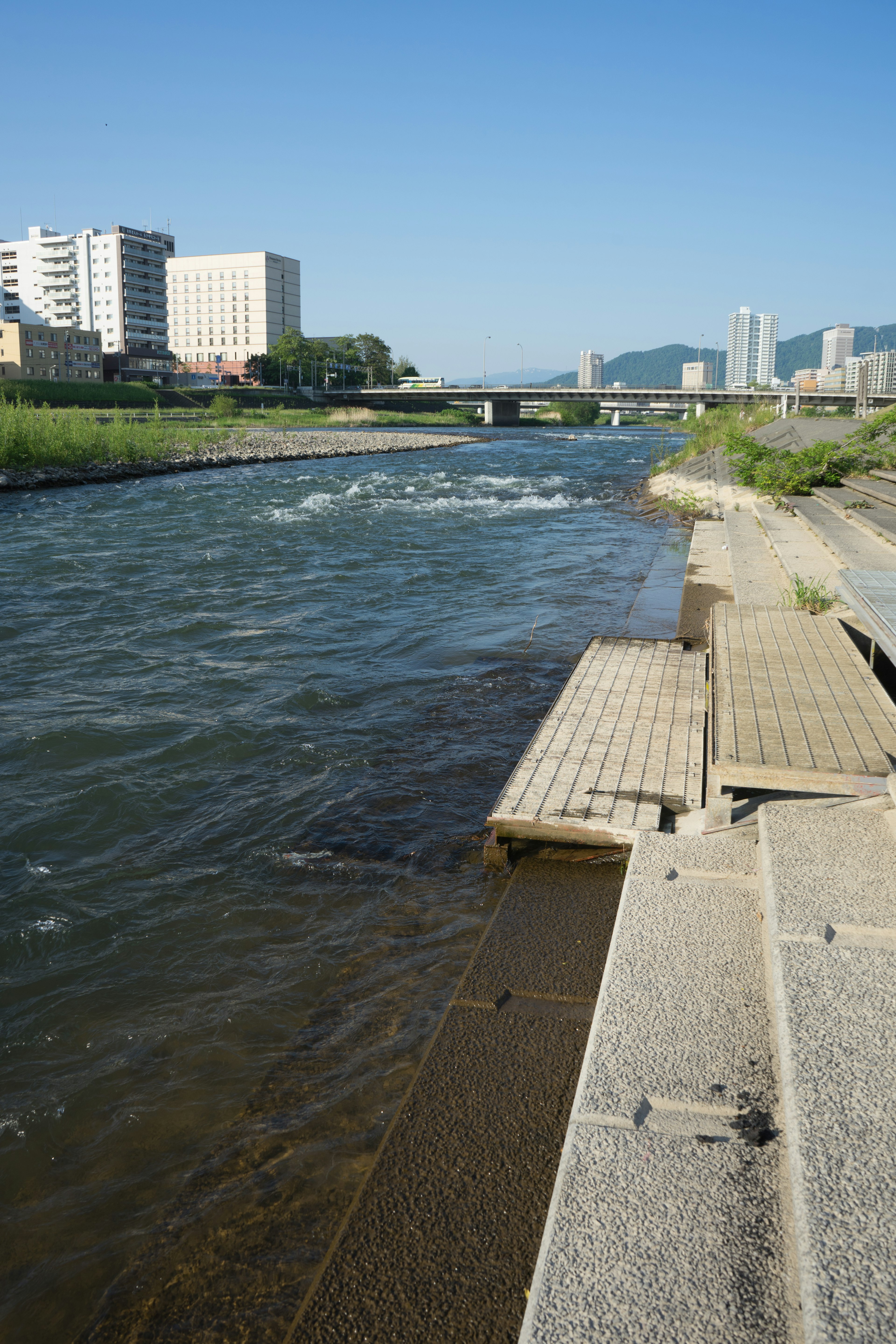 Vista escénica de un río con edificios y un puente al fondo