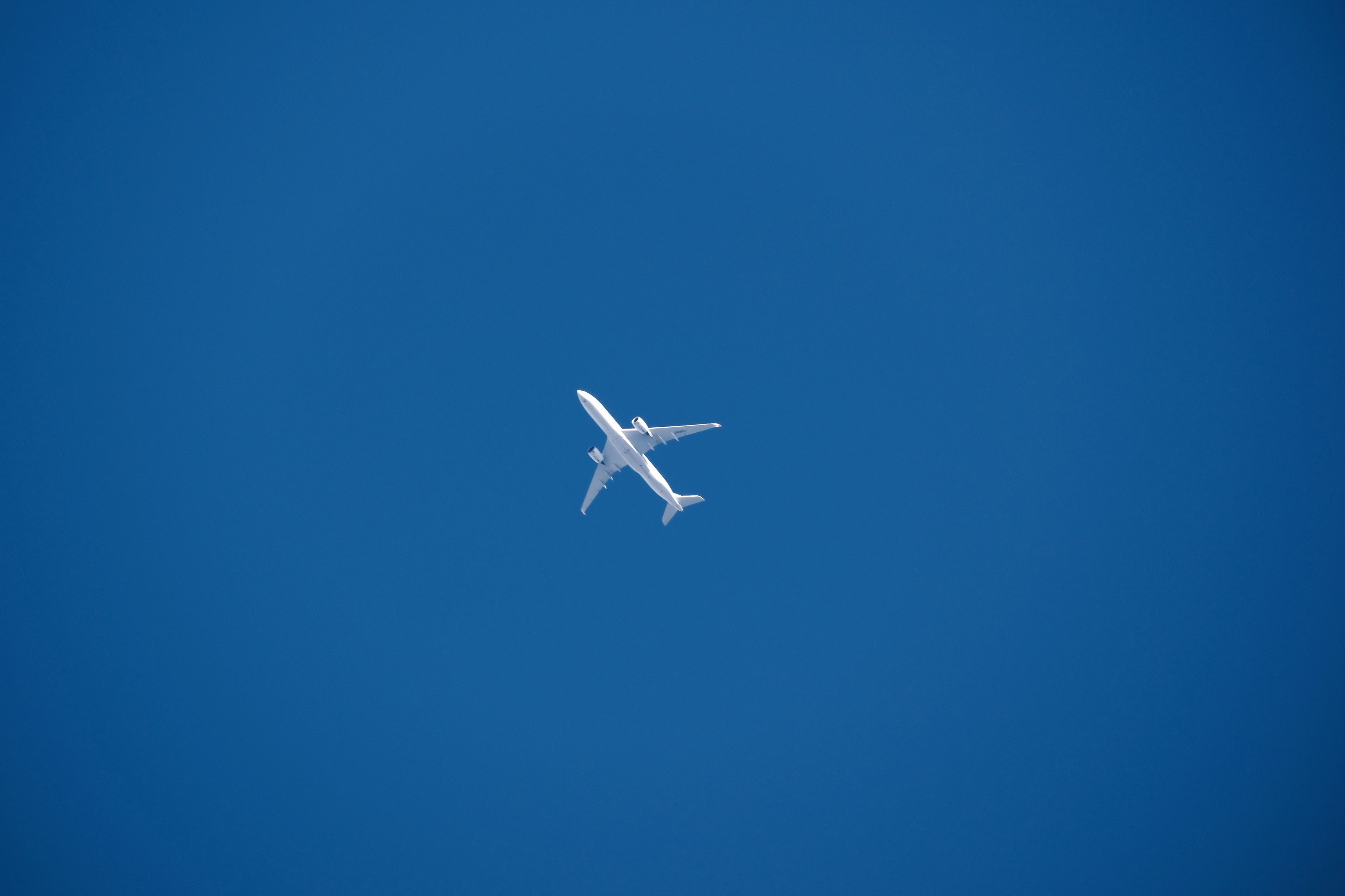 A white passenger airplane flying in a blue sky