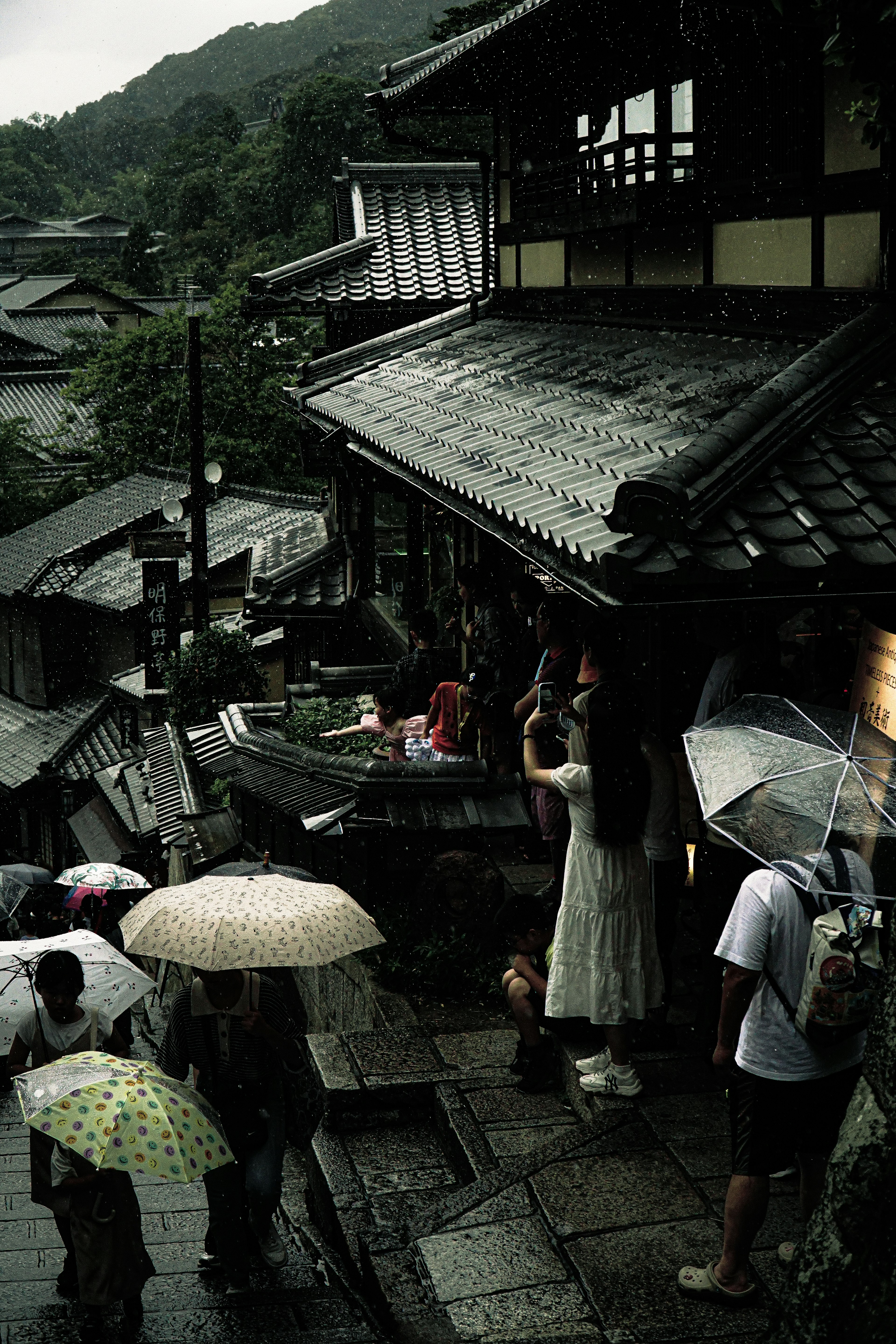 People with umbrellas in the rain near traditional Japanese buildings