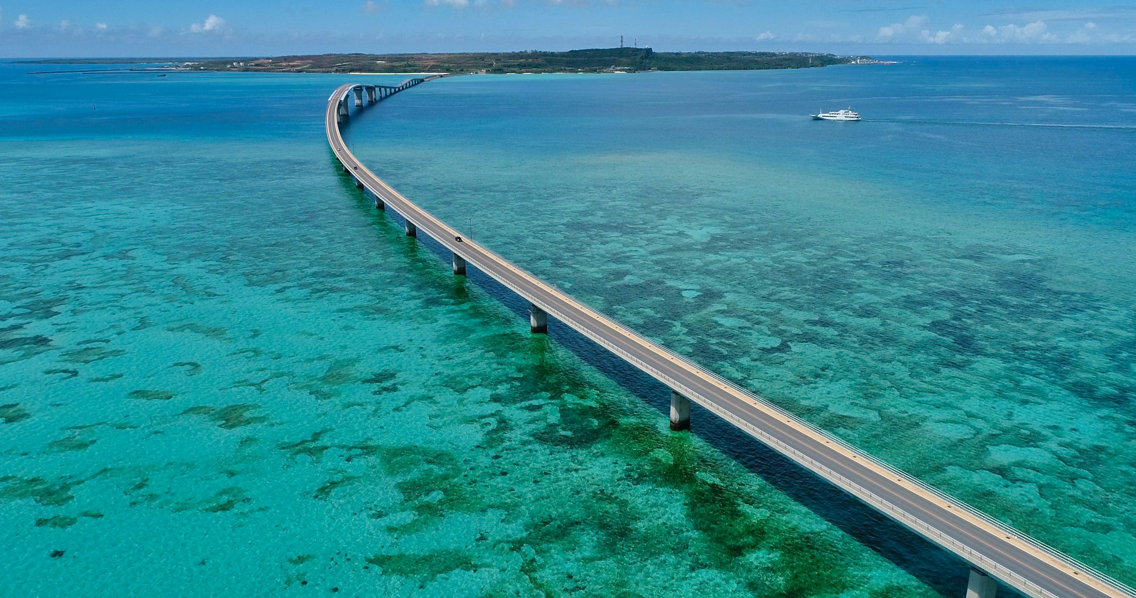 Pont courbe sur des eaux bleues claires avec des récifs coralliens