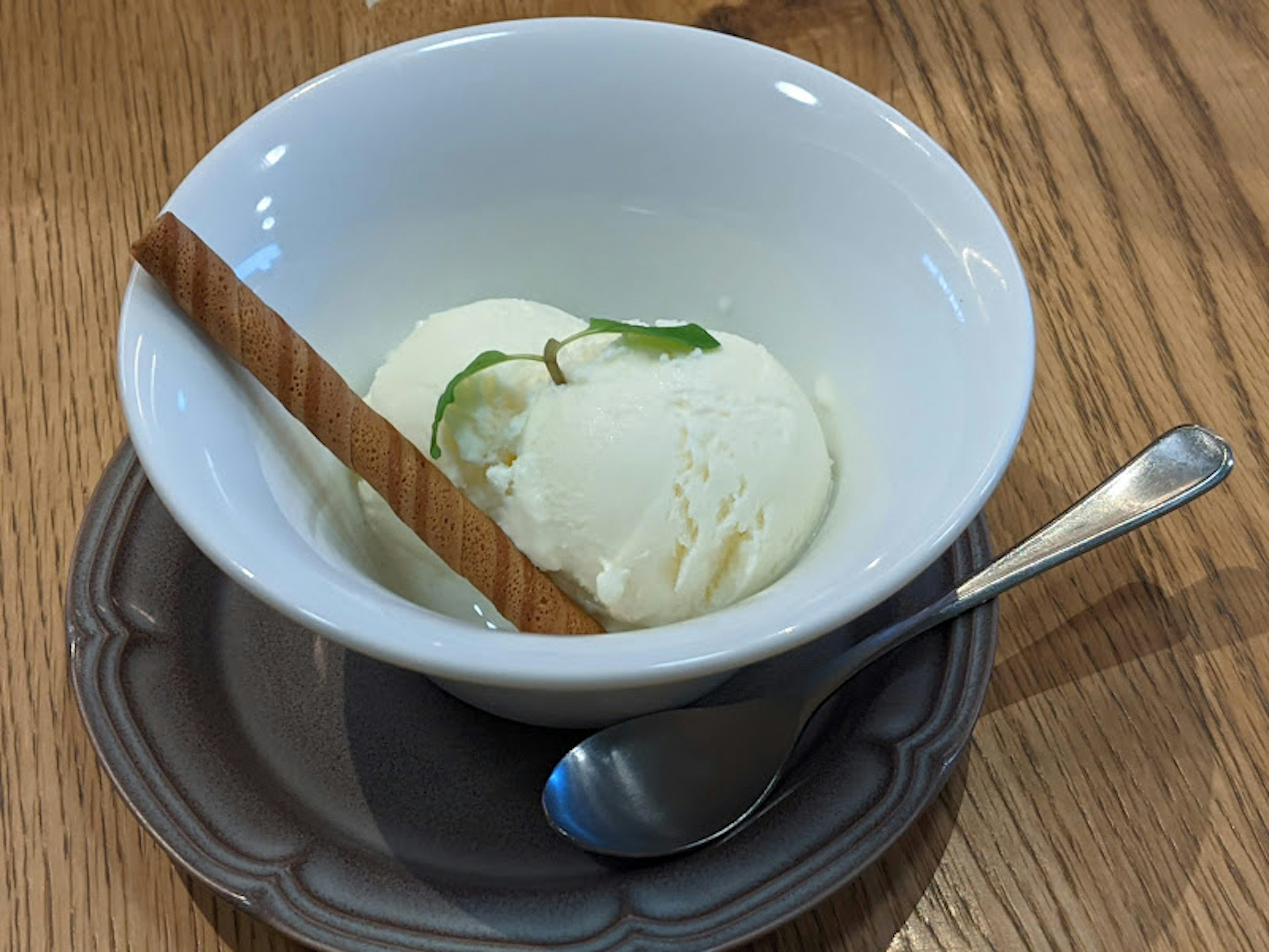 A bowl of white ice cream garnished with mint leaves and a cinnamon stick