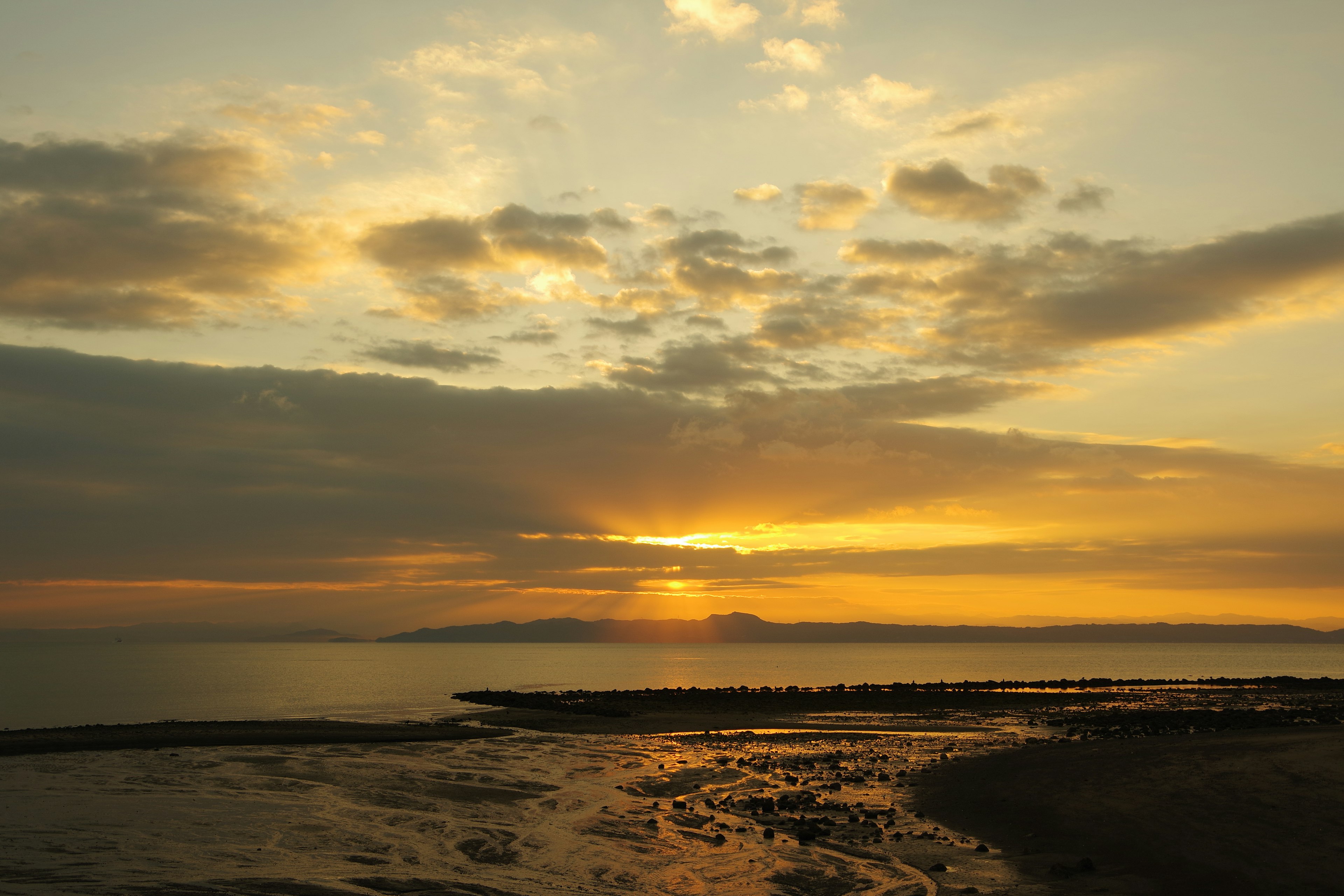 美しい夕日が海の水平線に沈む様子と雲のシルエット